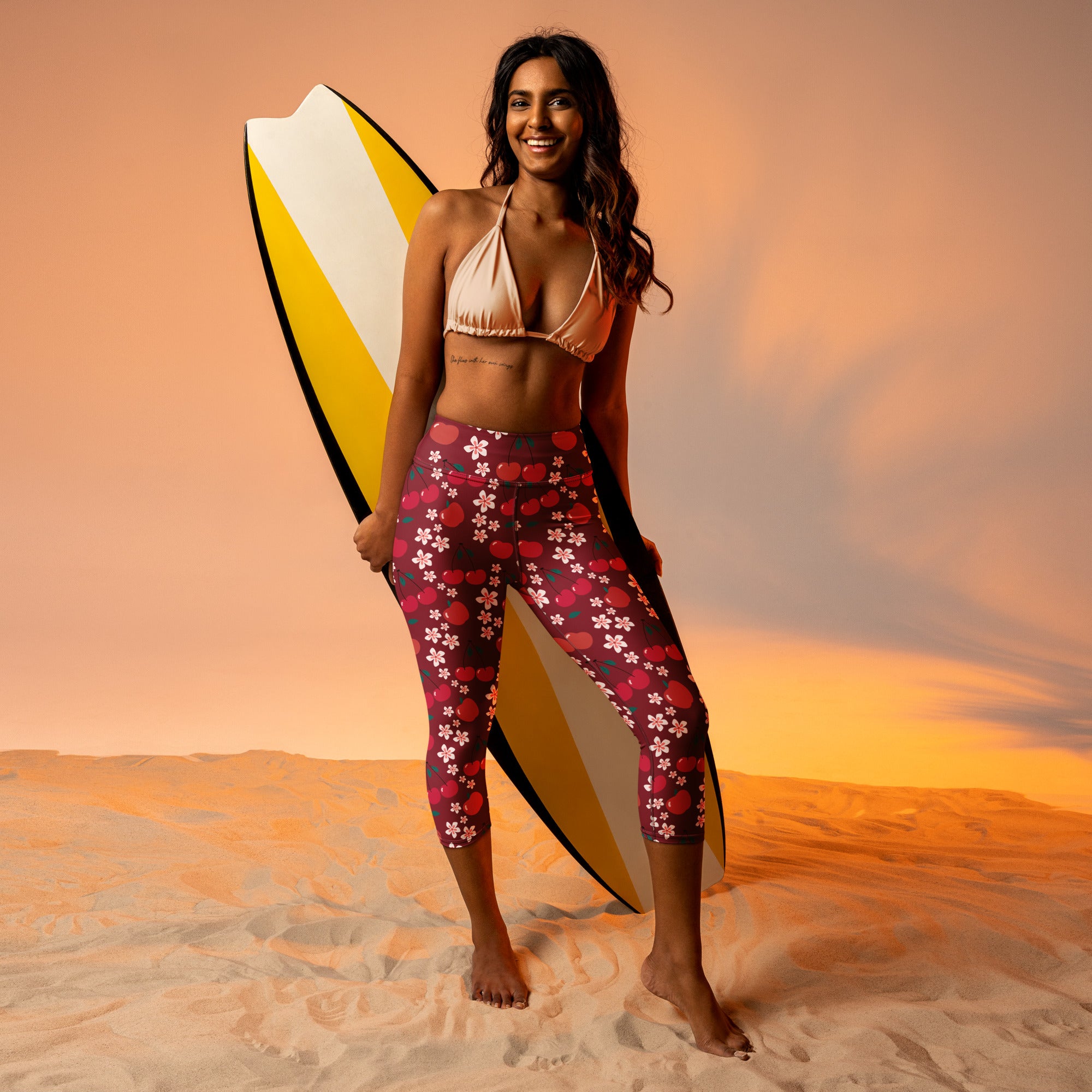 Woman wearing high-rise buttery soft yoga capri leggings with pink cherry blossom and polka dot patterns on dark red base