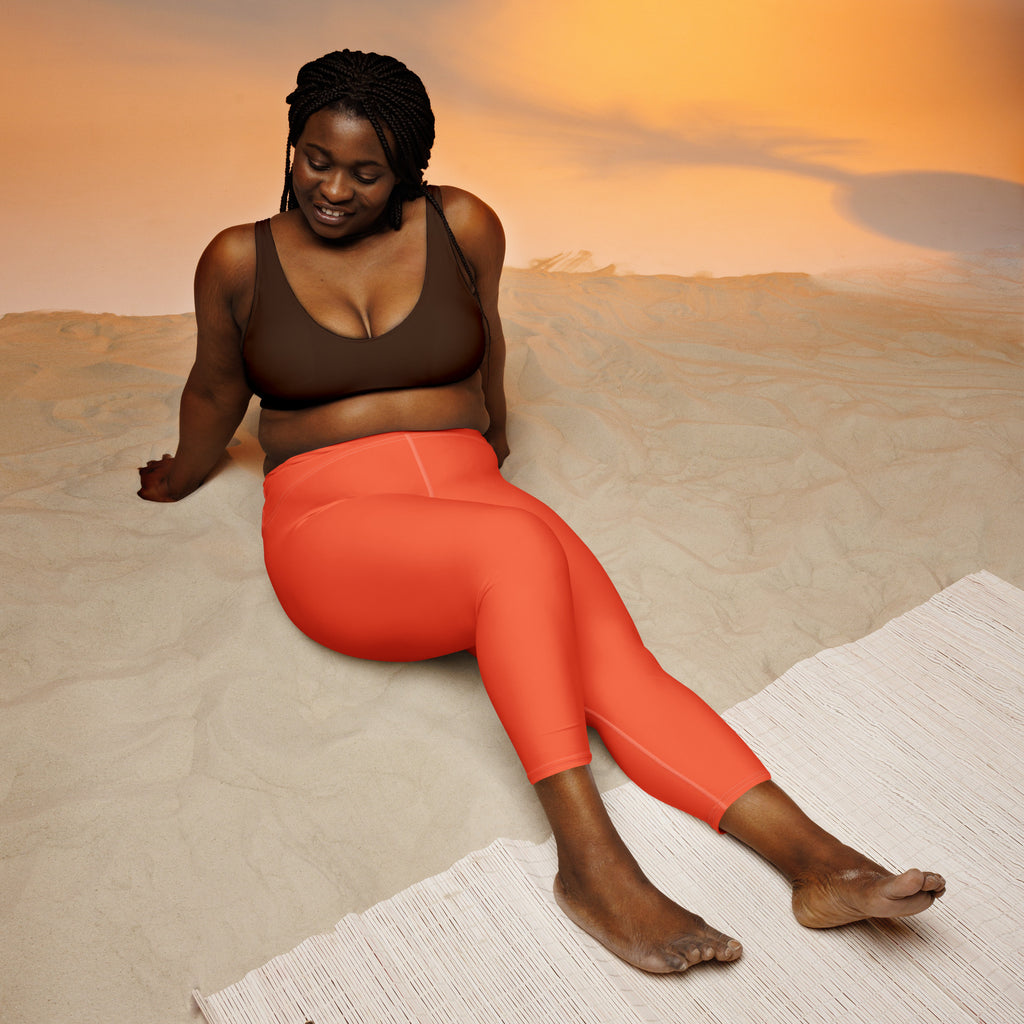 A pair of vibrant coral high-rise womens yoga capri leggings made from buttery soft moisture-wicking stretch fabric