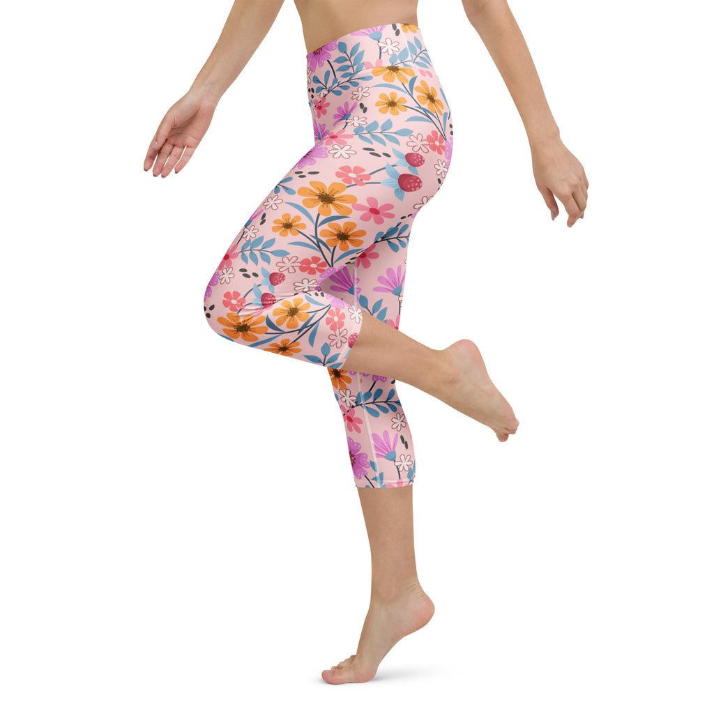 Women’s pink floral buttery soft yoga capri leggings with vibrant orange yellow purple flowers on light pink background