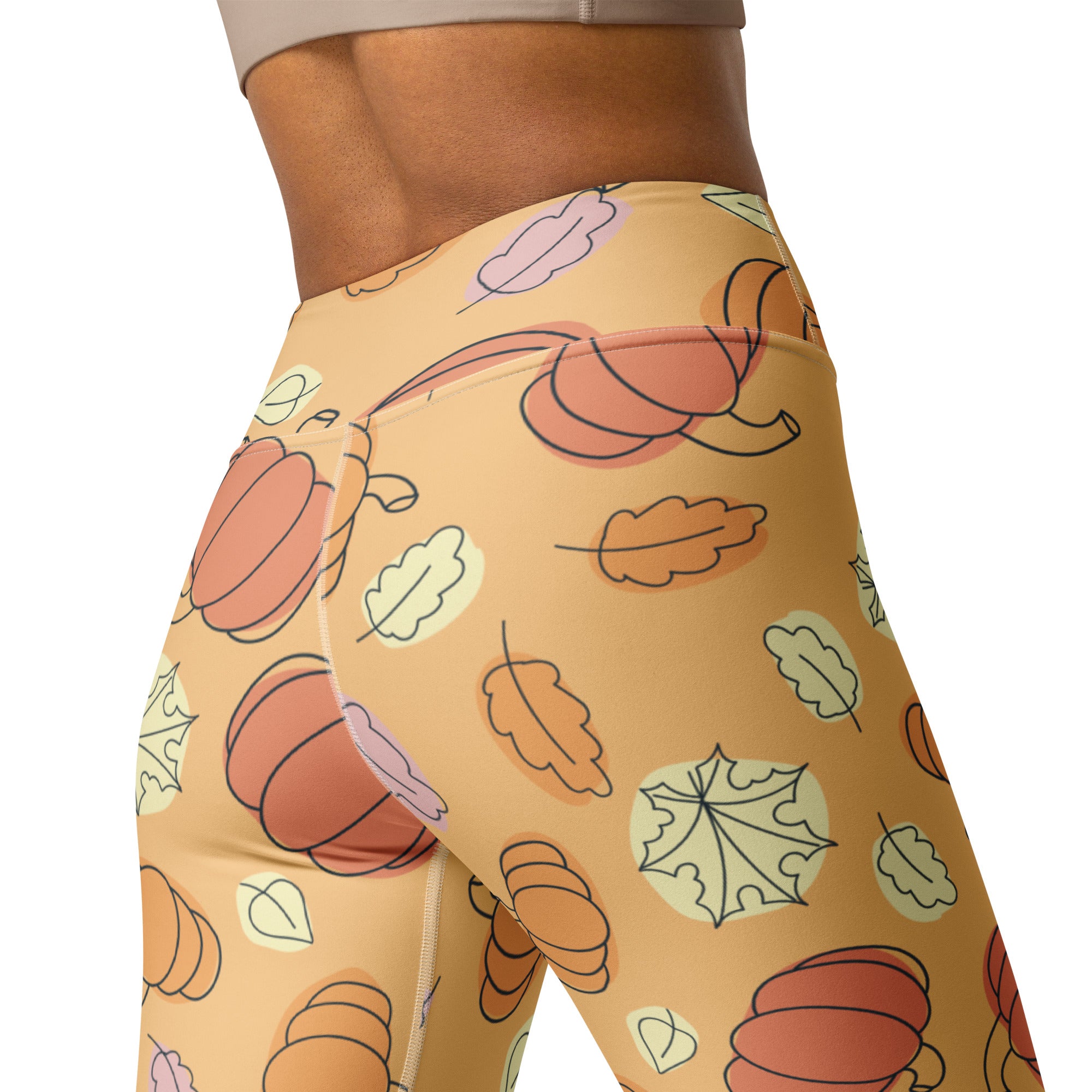 Women’s buttery soft tan yoga leggings featuring a playful autumn pattern of orange pumpkins and pastel leaves