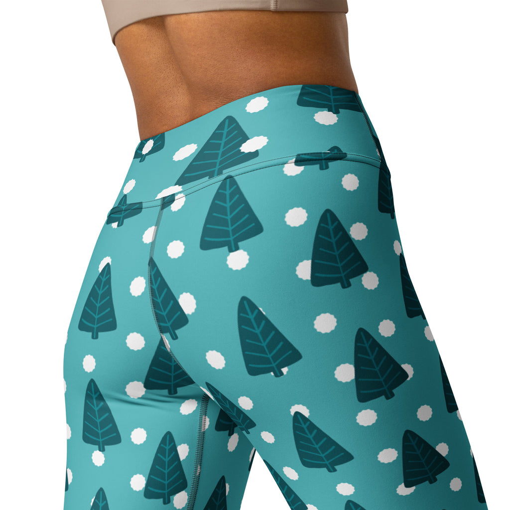 Women’s teal high-waisted yoga leggings with dark green pine tree and white snowflake pattern buttery soft fabric