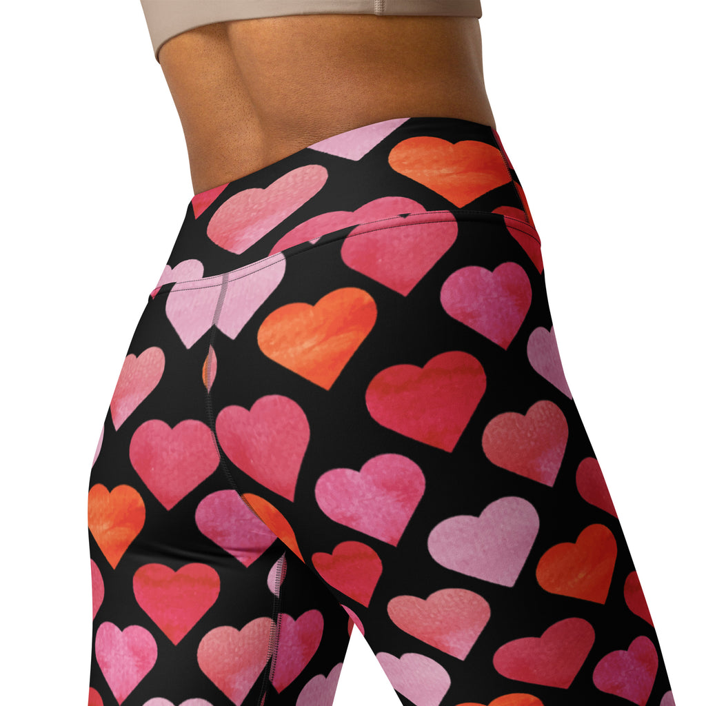 Black high-waisted women’s yoga leggings with vibrant watercolor hearts in pink coral and orange quick drying buttery soft