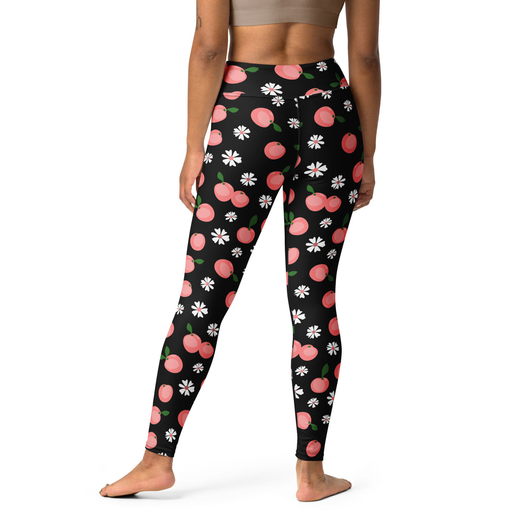 Black women’s buttery soft yoga leggings with playful pink peach and white daisy pattern on black fabric