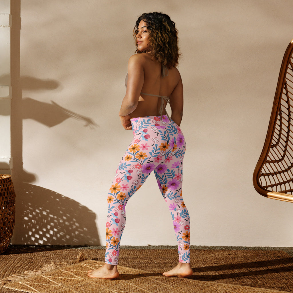 Women’s pink floral buttery soft yoga leggings with vibrant orange yellow and blue flower pattern on light pink background
