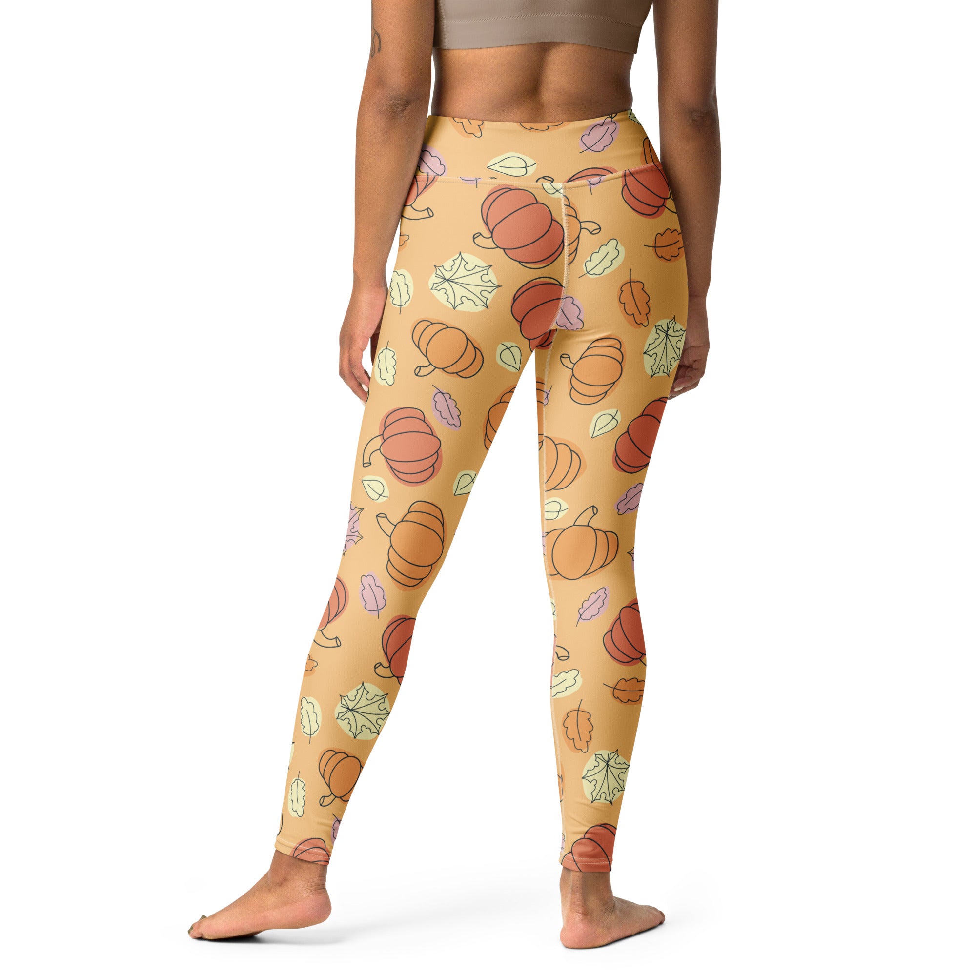 Tan buttery soft women’s yoga leggings with playful orange pumpkins and multicolored autumn leaves pattern