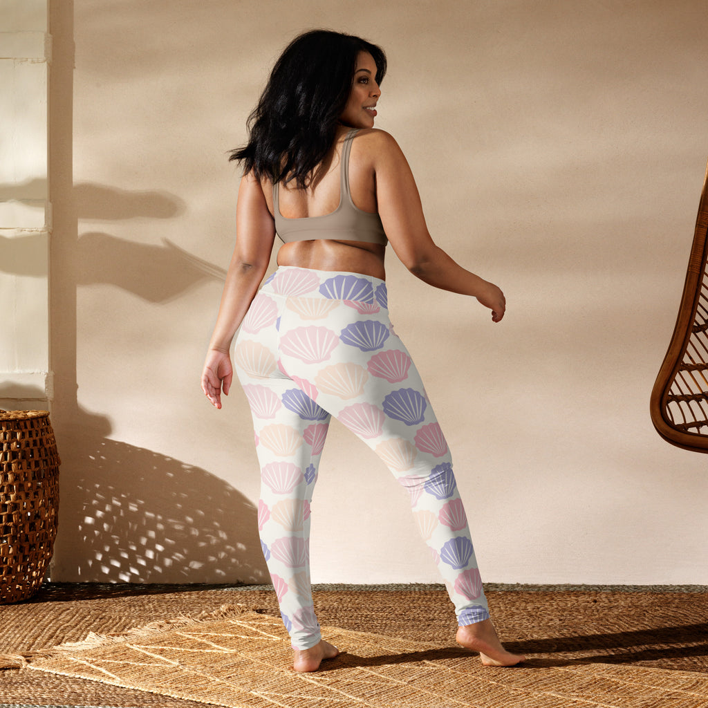 A pair of women’s white buttery soft yoga leggings with pastel pink and lavender seashell pattern