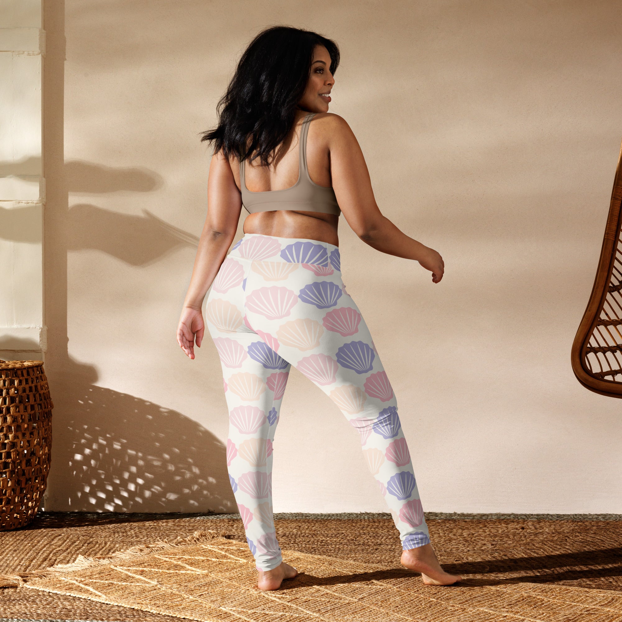 A pair of women’s white buttery soft yoga leggings with pastel pink and lavender seashell pattern