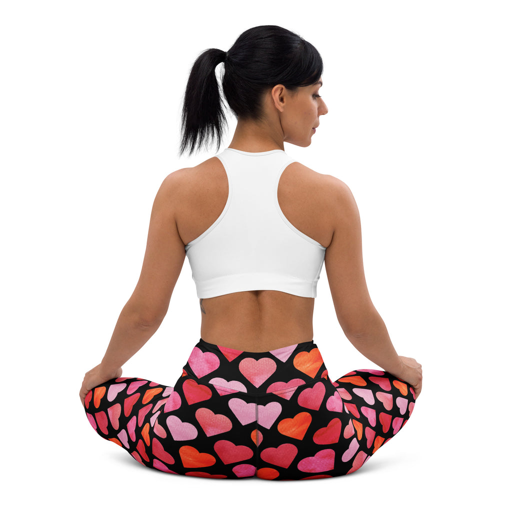Women’s high waisted black leggings with vibrant pink and orange watercolor hearts made of buttery soft quick drying fabric