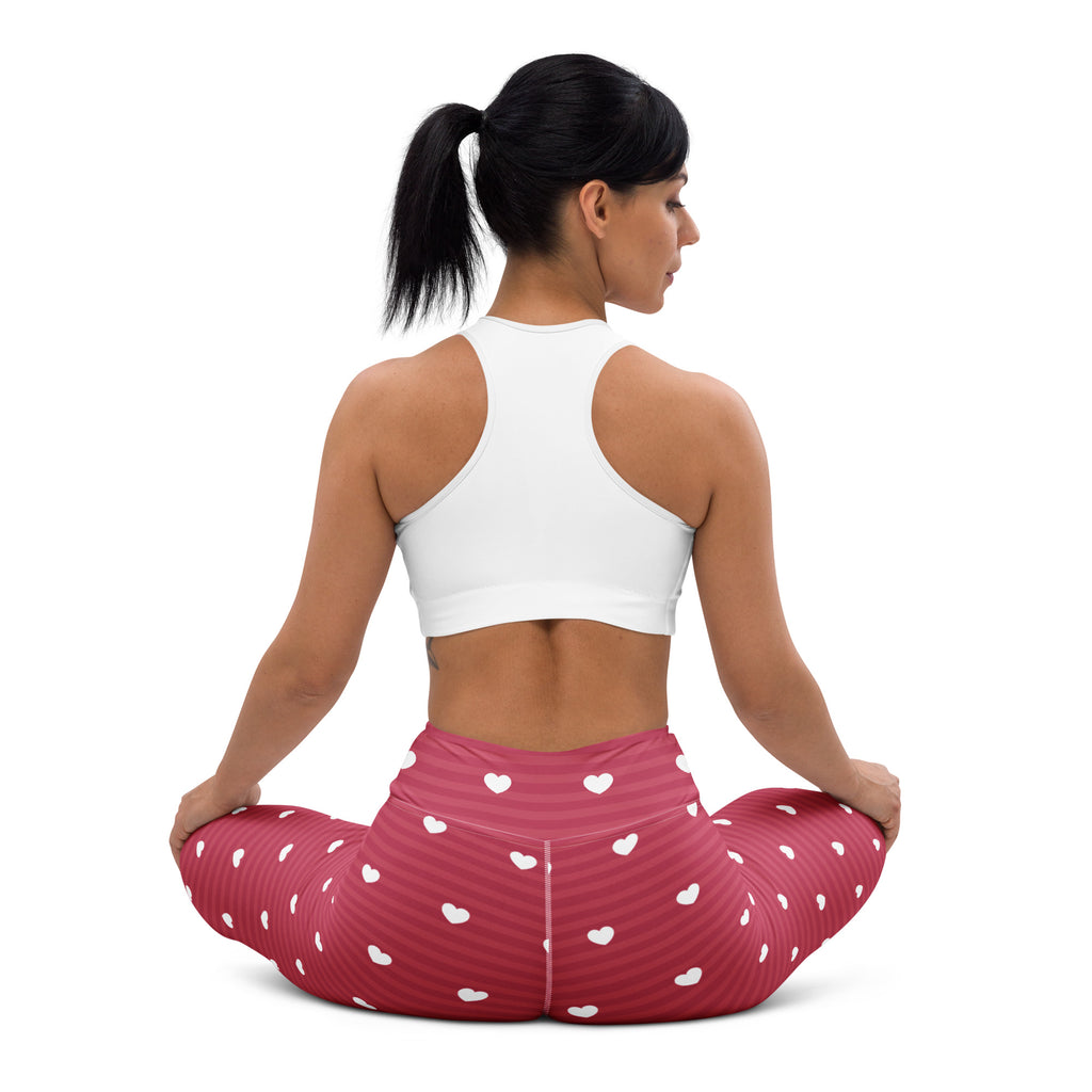 A pair of women’s pink high waisted buttery soft yoga leggings with white heart patterns and subtle vertical stripes