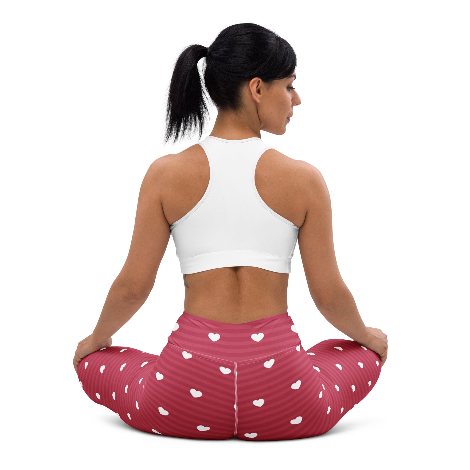 A pair of women’s pink high waisted buttery soft yoga leggings with white heart patterns and subtle vertical stripes