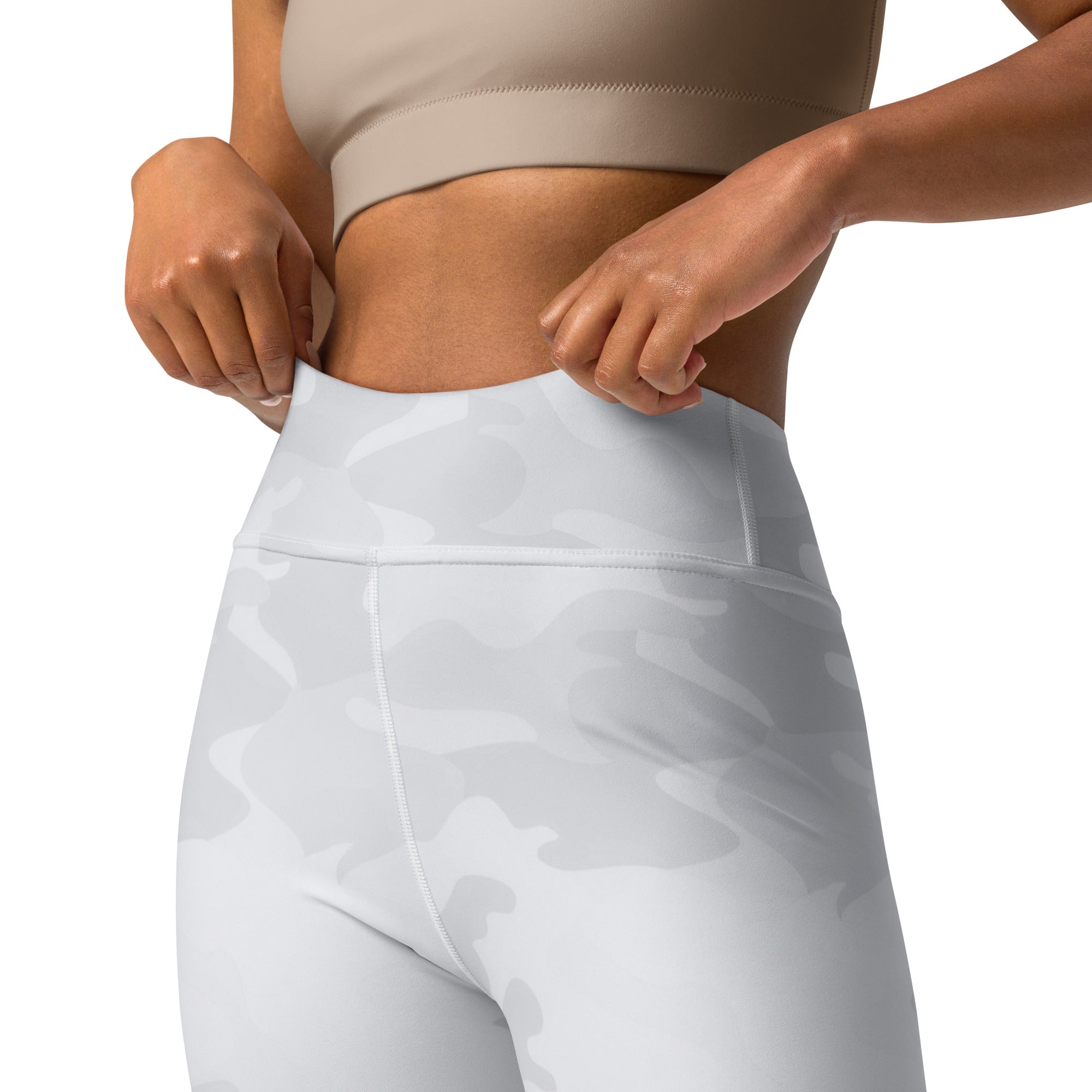 Person wearing white leggings and a beige top on a plain background