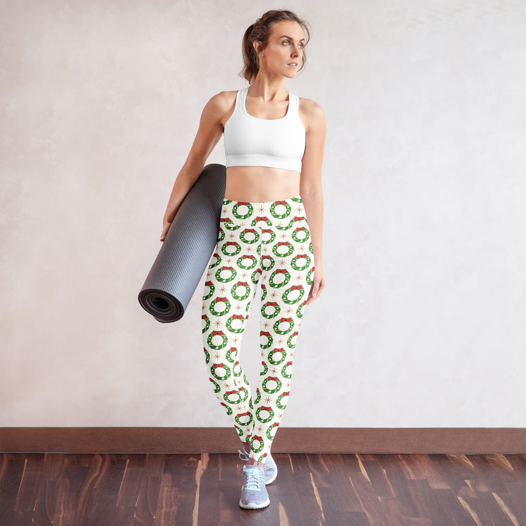 White buttery soft women’s yoga leggings with green wreath and red bow pattern on off-white background