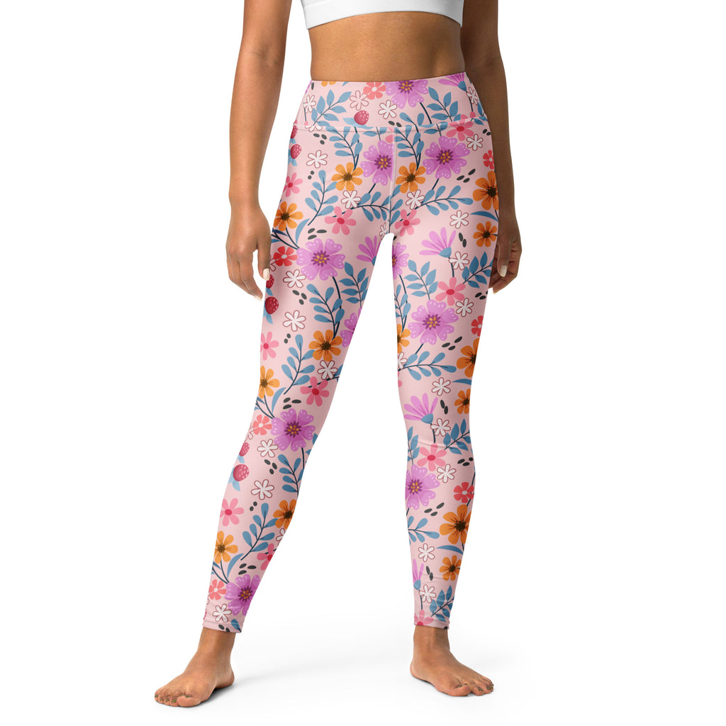 Women’s pink floral buttery soft yoga leggings with vibrant purple orange and blue flower pattern on light pink background