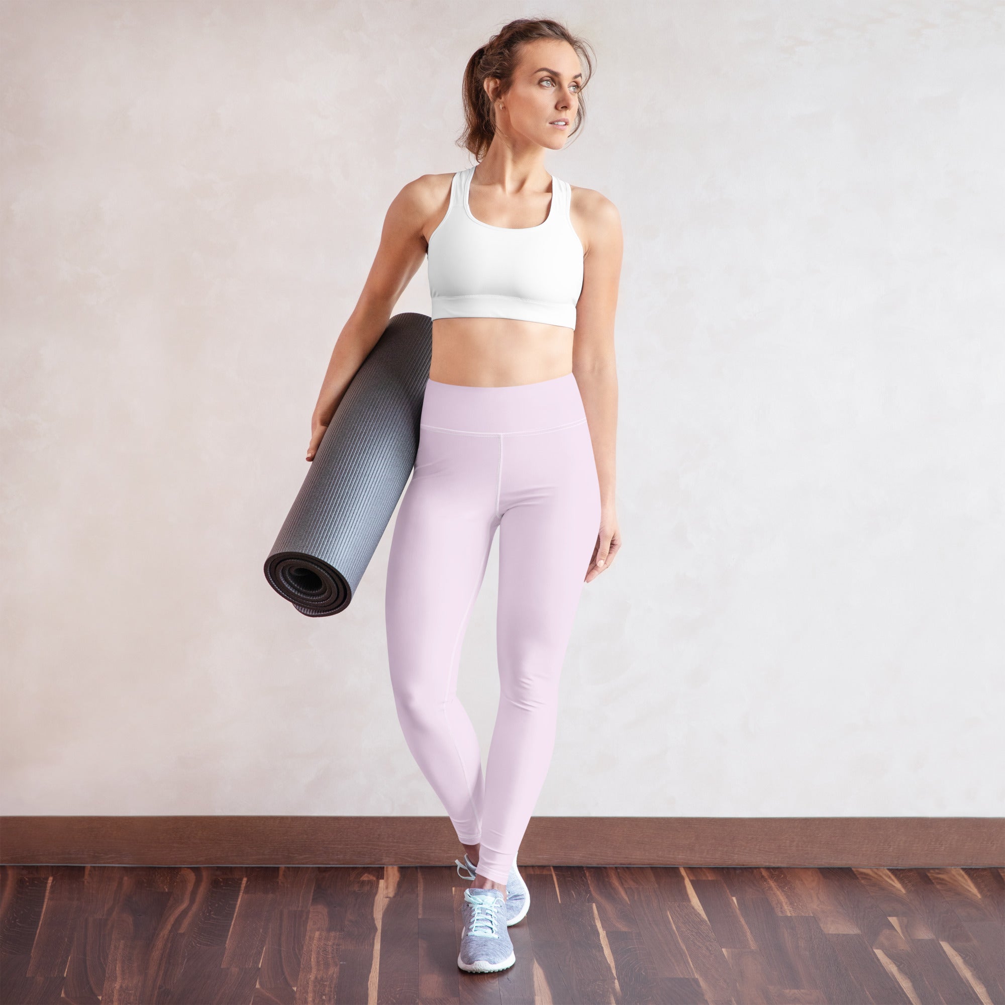 A rolled-up dark gray textured yoga mat paired with women’s light purple buttery soft yoga leggings