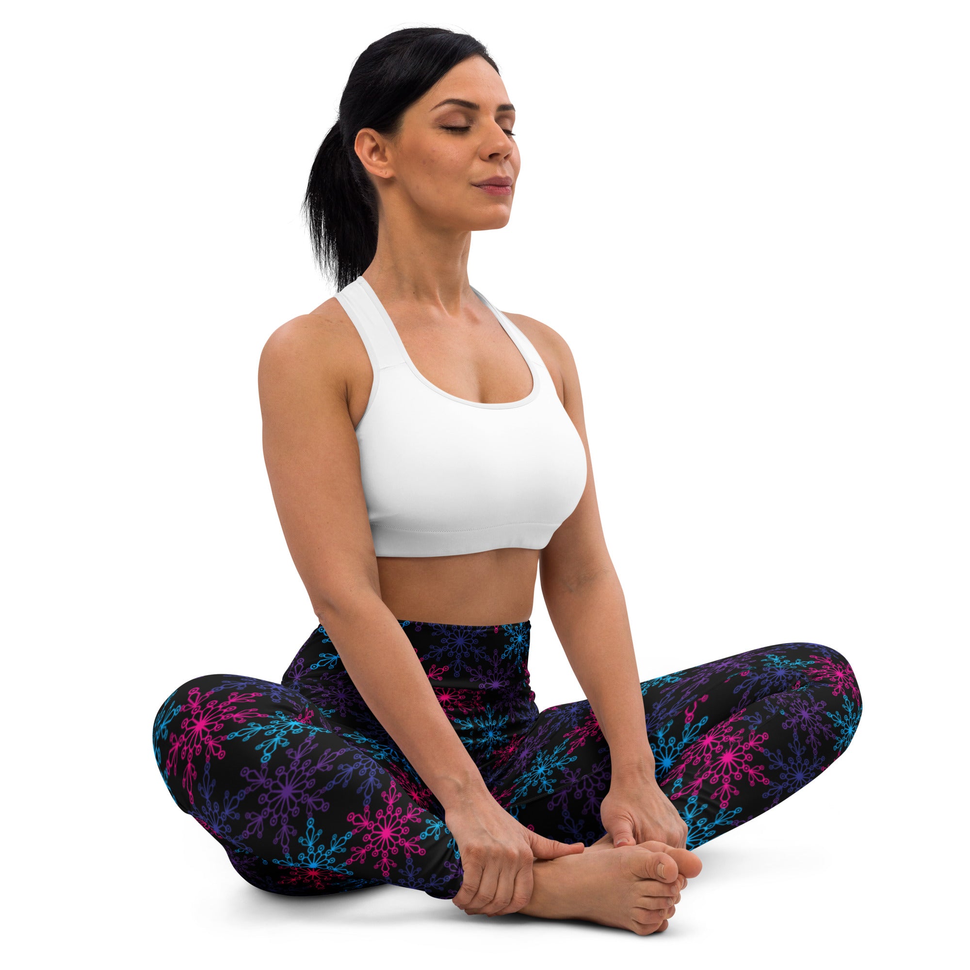 Woman wearing white sports bra and black buttery soft yoga leggings with colorful neon snowflake winter pattern
