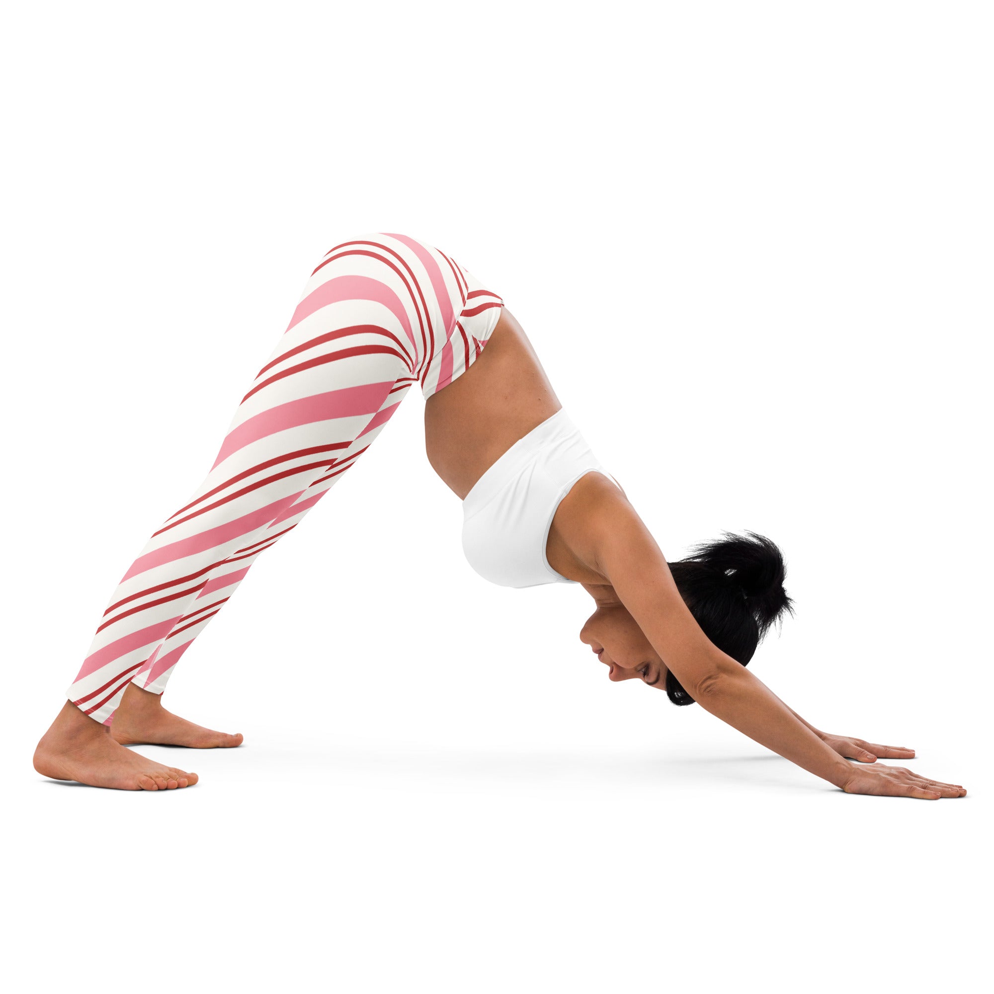 A woman wearing women’s candy cane stripe buttery soft yoga leggings in pink and white stripes in a yoga pose