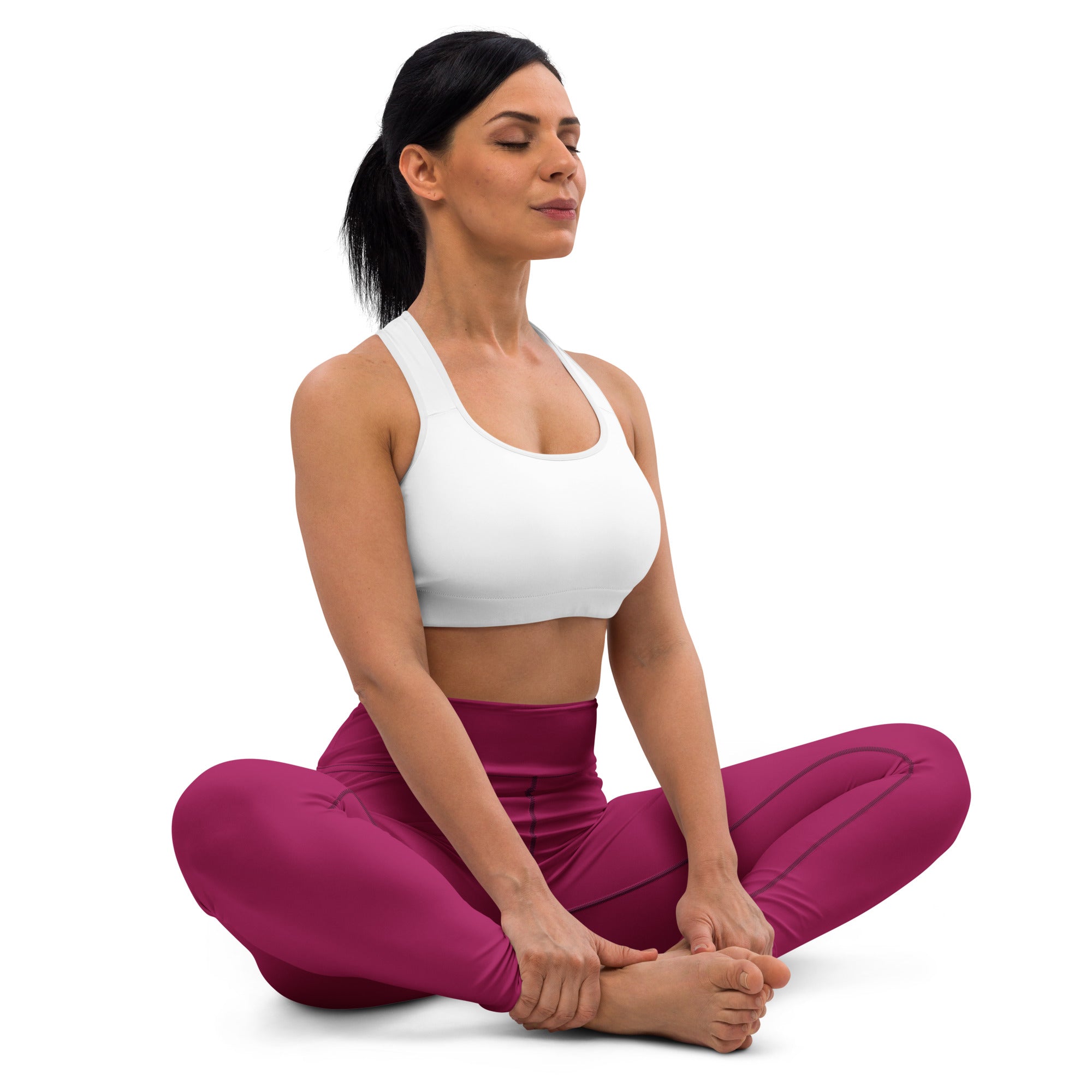 A woman in a seated yoga pose wearing dark magenta buttery soft yoga leggings and a white sports bra