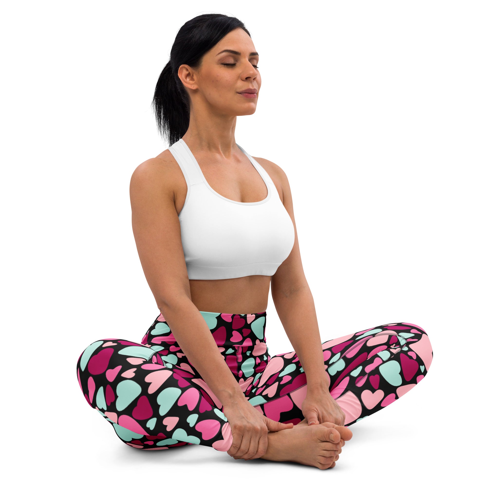 Woman wearing white sports bra and colorful hearts buttery soft yoga leggings with quick drying high waisted comfort