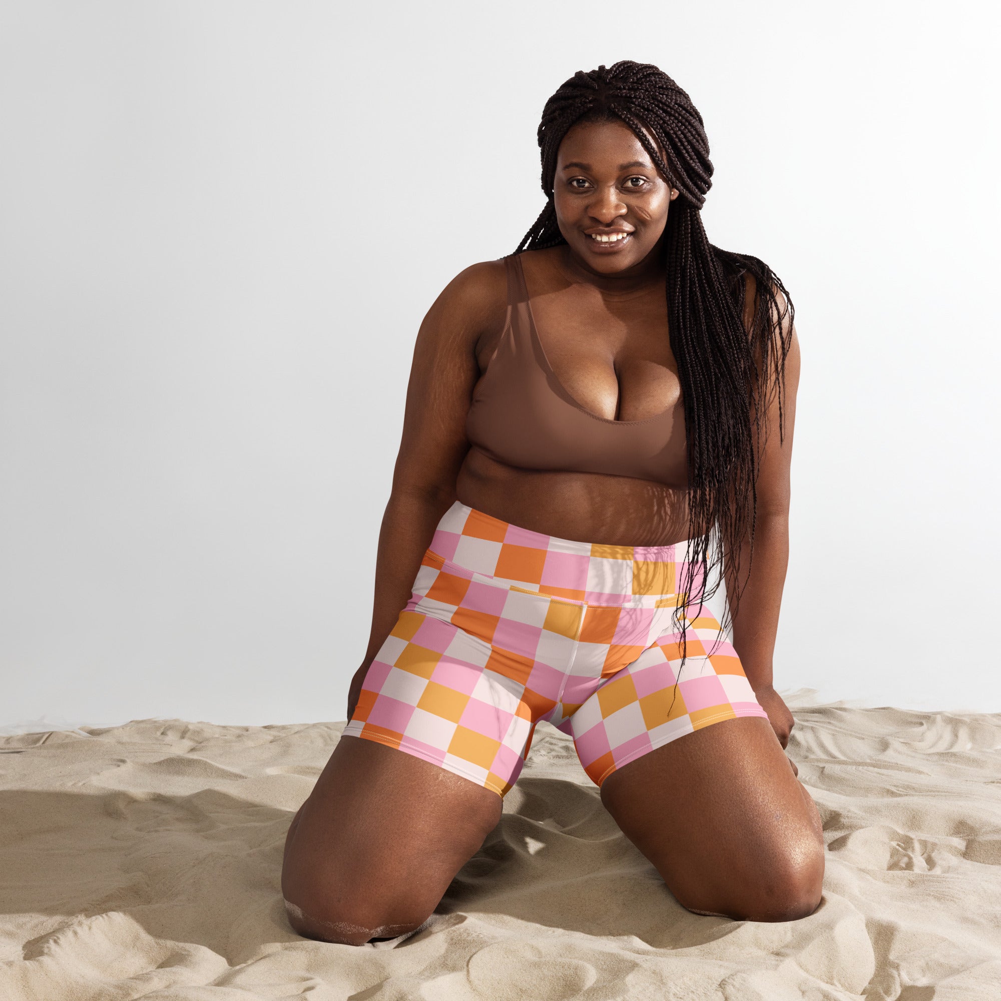 A pair of women’s high waisted pink and orange checkered yoga shorts made from stretchy buttery soft fabric