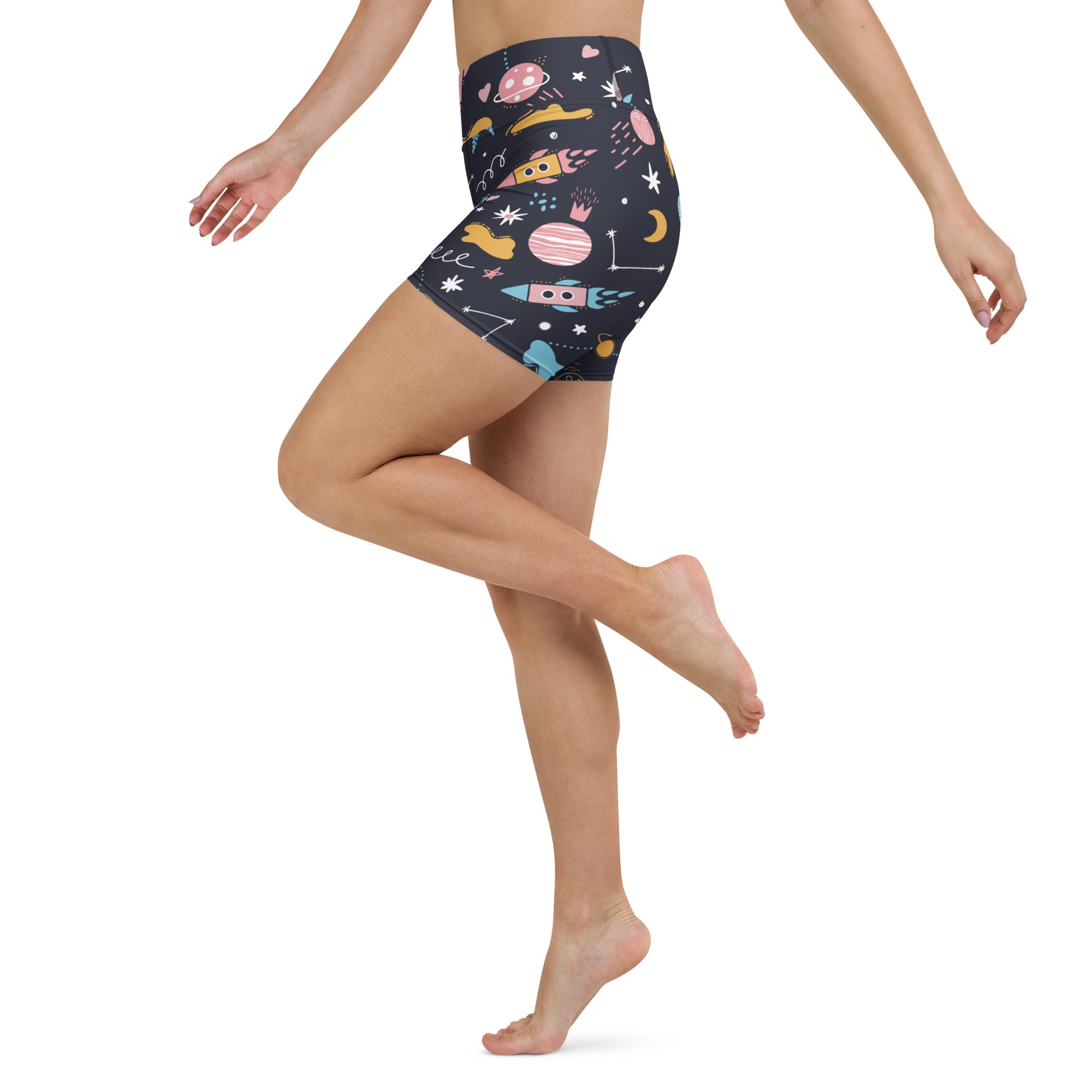 Dark blue high-waisted buttery soft women’s outer space yoga shorts with pastel pink yellow and teal rocket and planet pattern