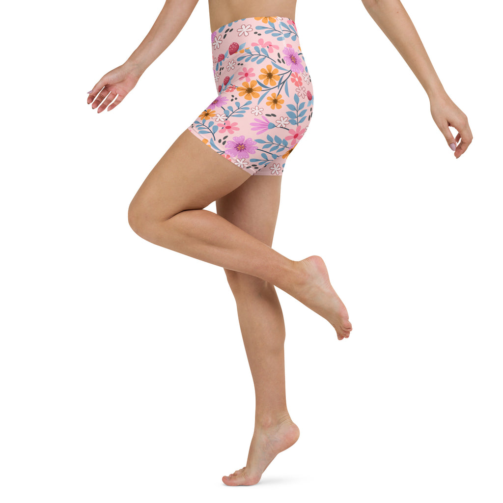 Women’s pink floral high-waisted buttery soft yoga shorts with vibrant orange yellow and purple flowers on light pink background