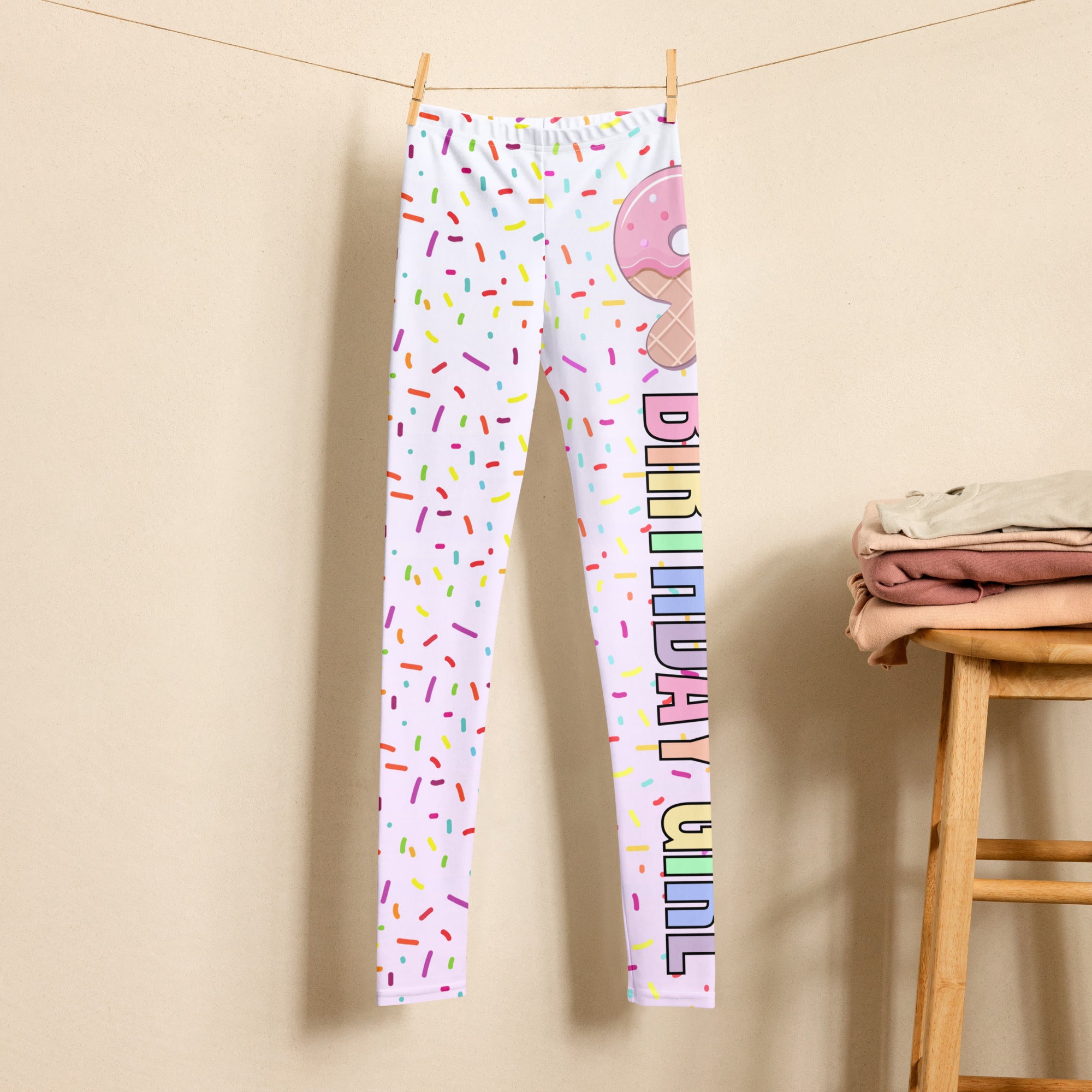 White buttery soft leggings with colorful sprinkle pattern and pink donut birthday girl graphic on one leg
