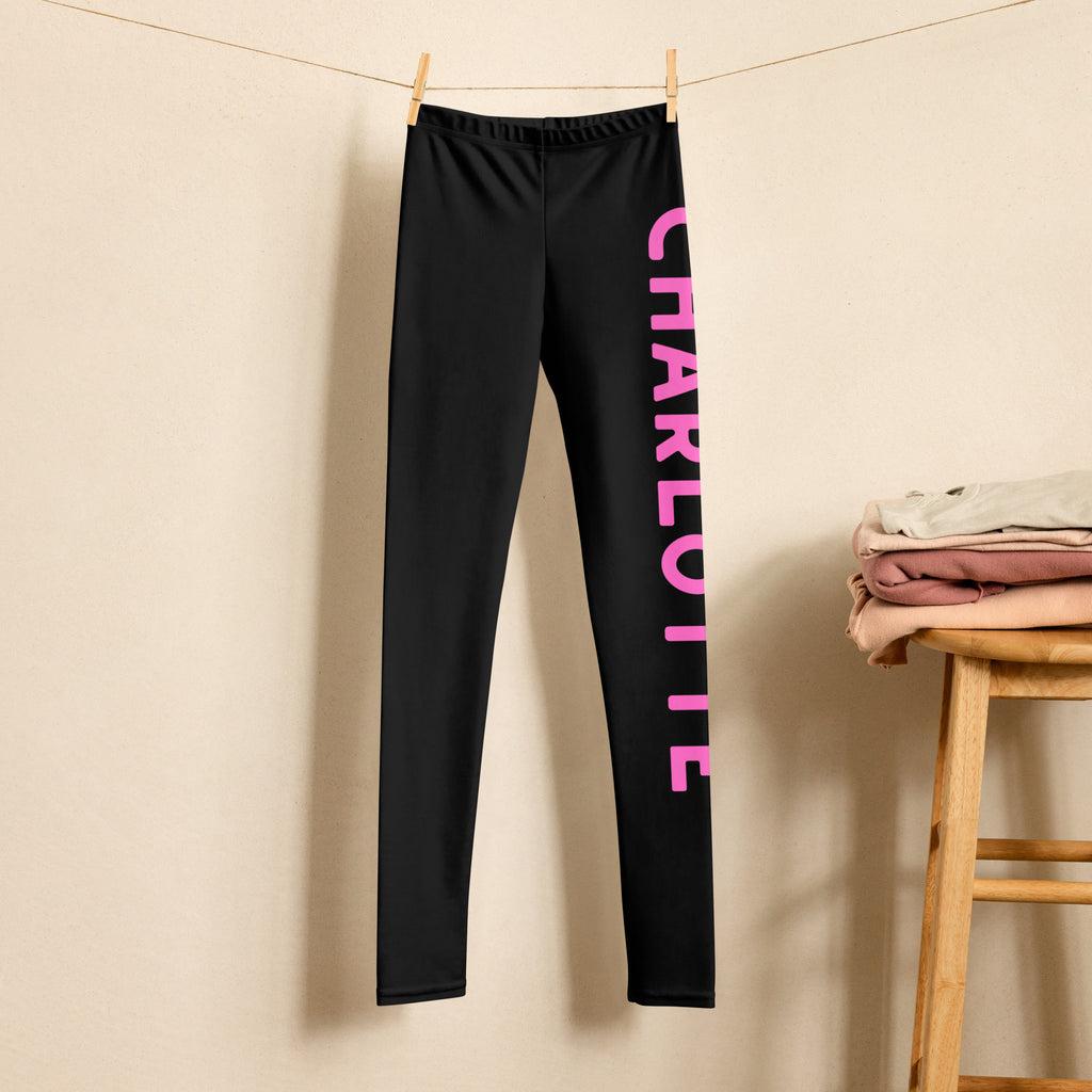 Girls custom color and name buttery soft black leggings with bold pink vertical lettering spelling charlotte