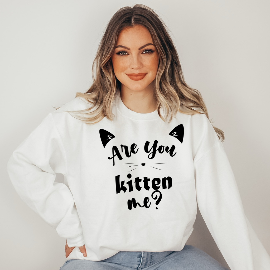 Woman wearing a white sweatshirt with text and cat ears design on a plain background