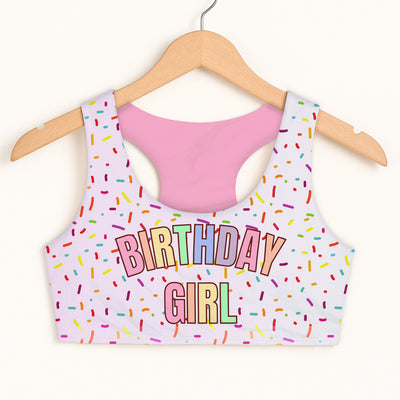 White quick drying double layered sports bra with pink interior colorful sprinkles and birthday girl rainbow letters