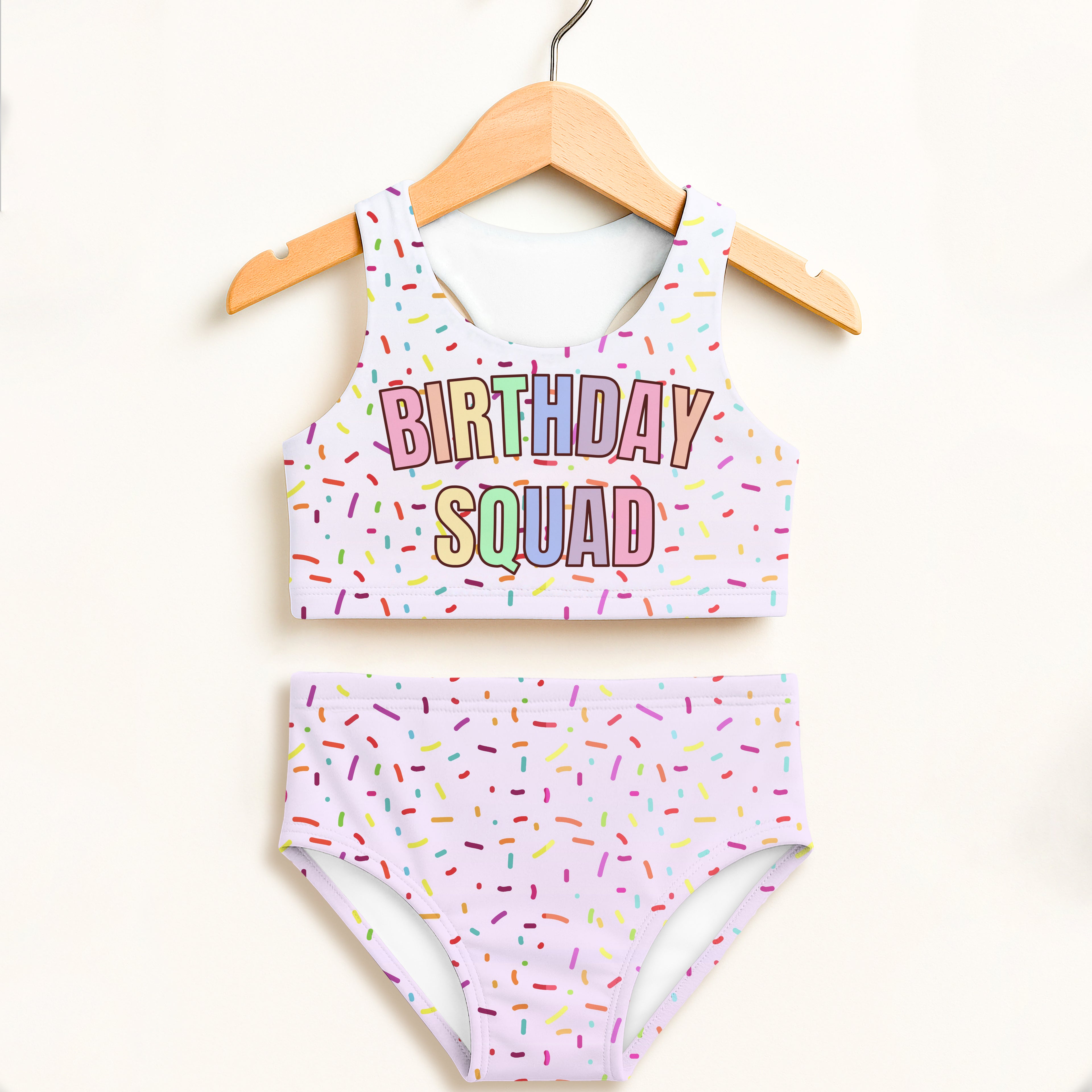 Pastel lavender two piece swimsuit set with rainbow sprinkle print birthday squad text and upf 50 plus protection