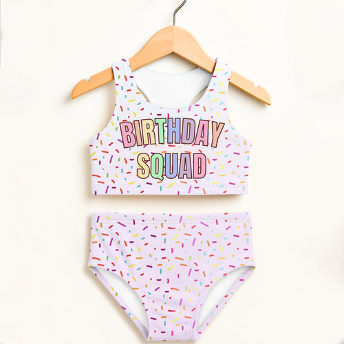 Pastel lavender two piece swimsuit set with rainbow sprinkle print birthday squad text and upf 50 plus protection