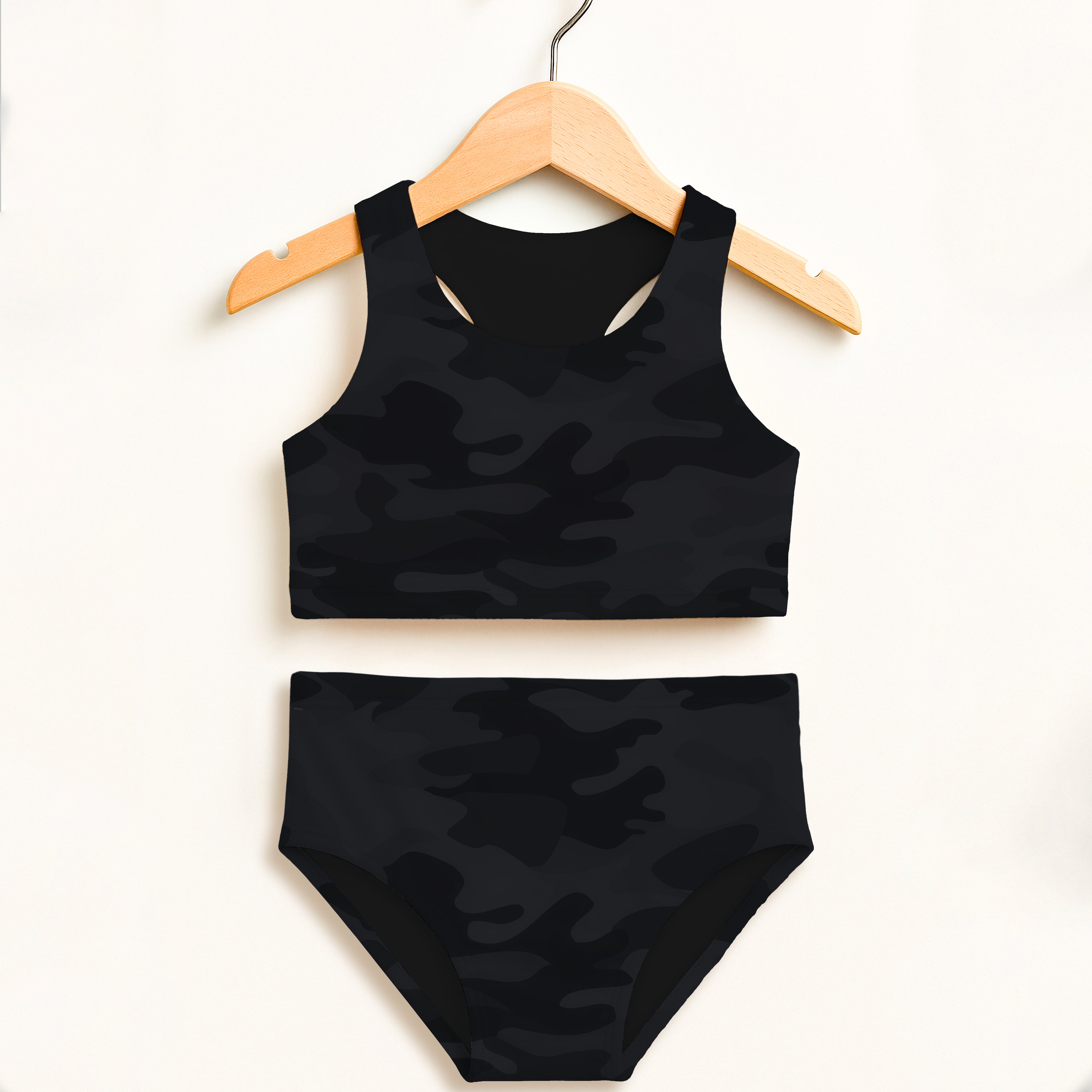Girls black camouflage two piece swimsuit set hanging on wooden hanger with double layered upf 50 plus fabric