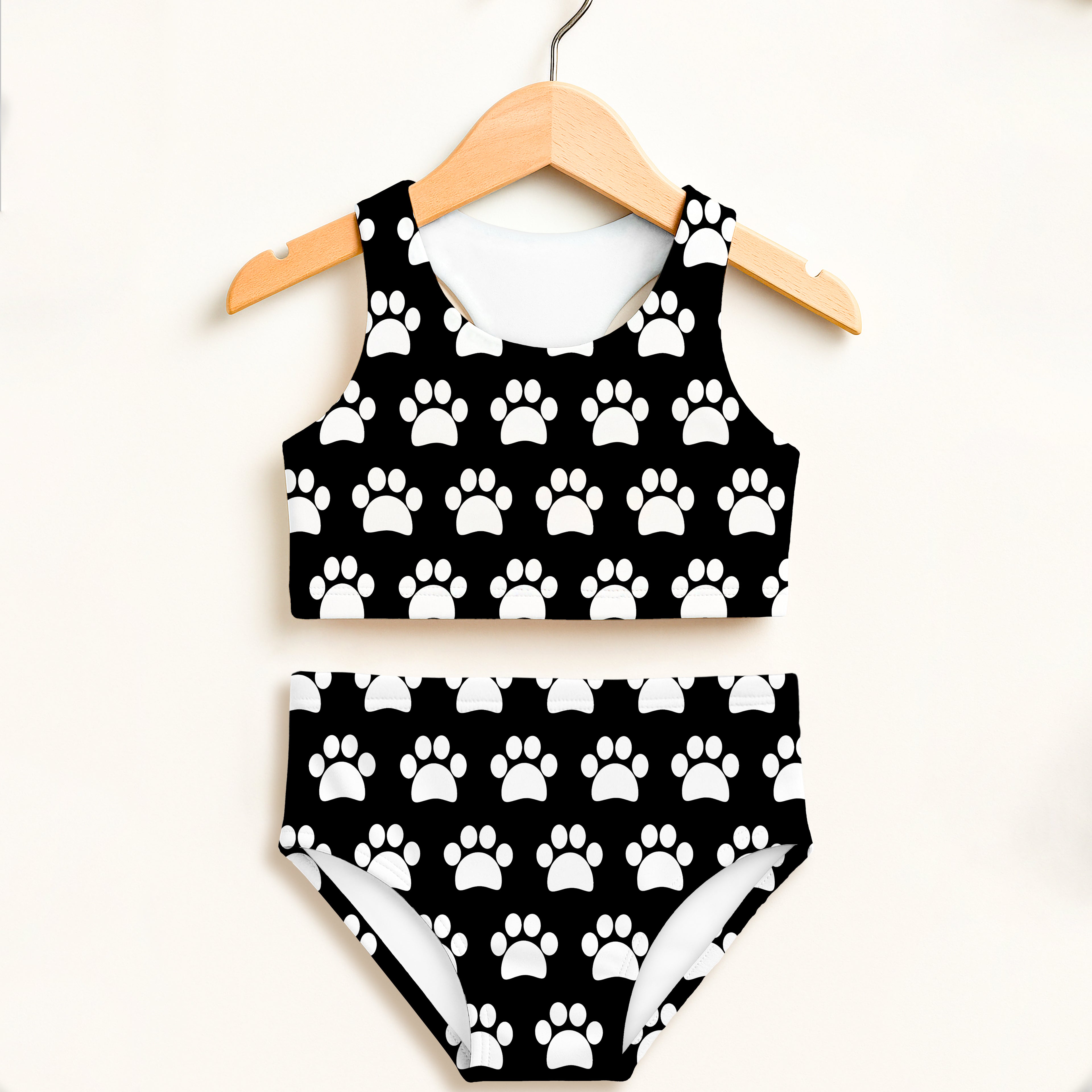Girls black and white paw print two piece swimsuit hanging on wooden hanger with double layered upf 50+ fabric