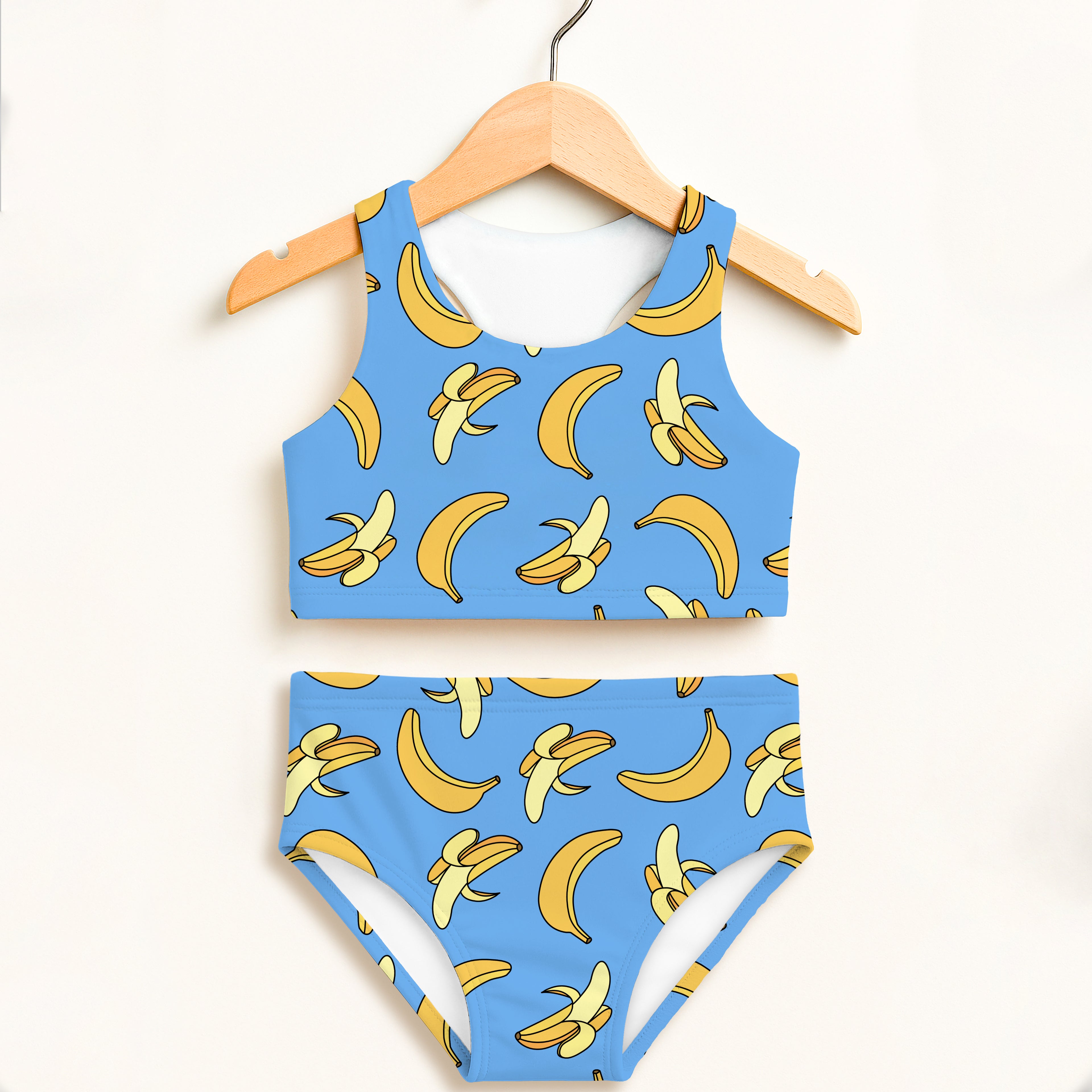 Girls blue banana-print two-piece swimsuit hanging on wooden hanger with double layered upf 50+ high waisted comfort