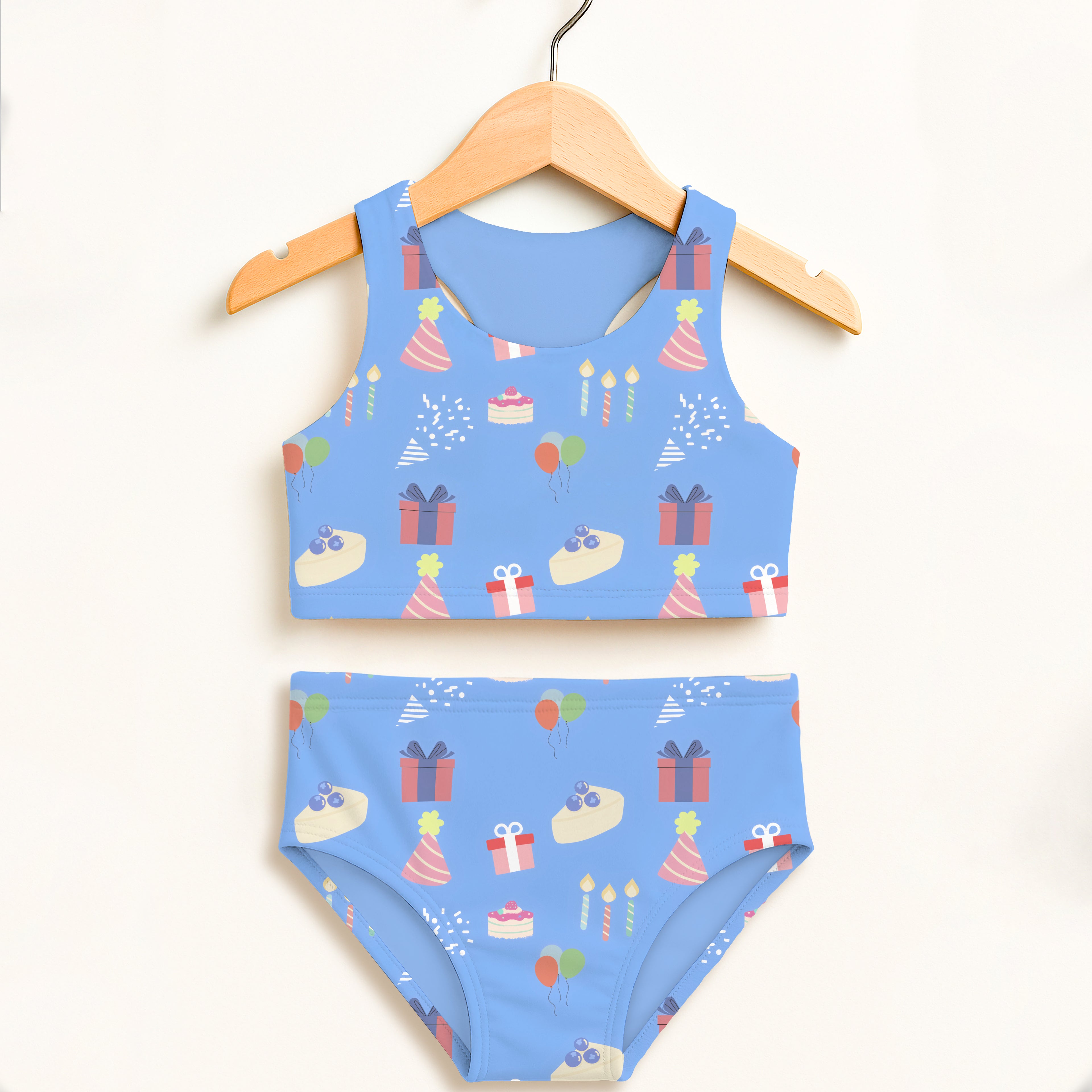 Girls blue birthday party two piece swimsuit with playful party hats gifts cakes and balloons on light blue fabric