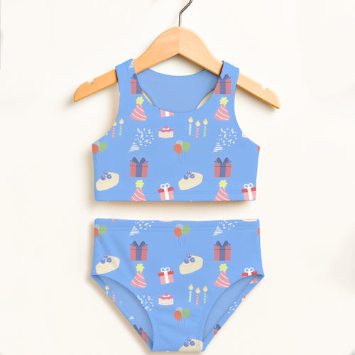 Girls blue birthday party two piece swimsuit with playful party hats gifts cakes and balloons on light blue fabric