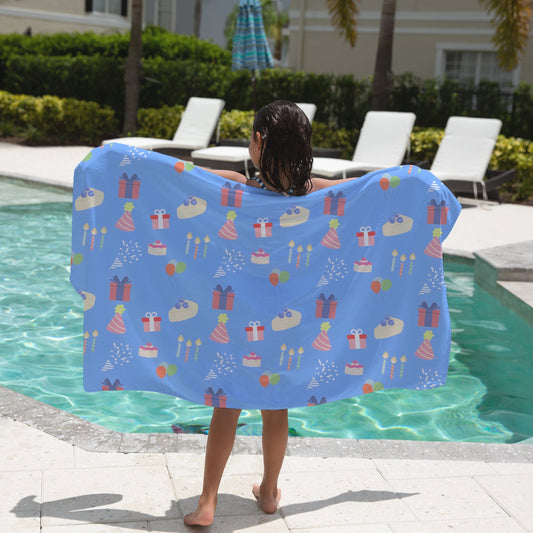 Person holding a blue birthday patterned towel by a poolside