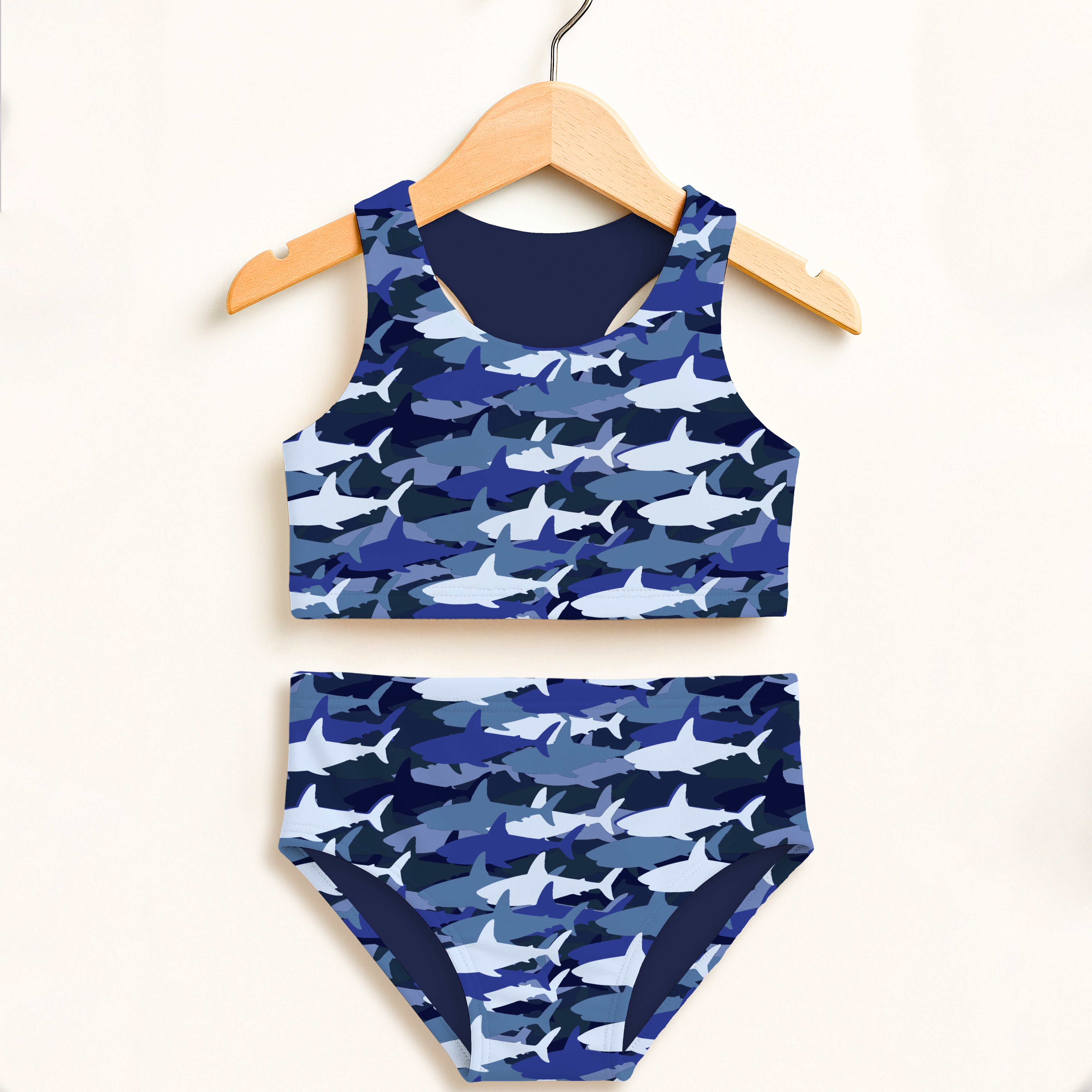 Girls blue and white shark camouflage two piece swimsuit hanging on wooden hanger with double layered fabric and UPF 50+ protection