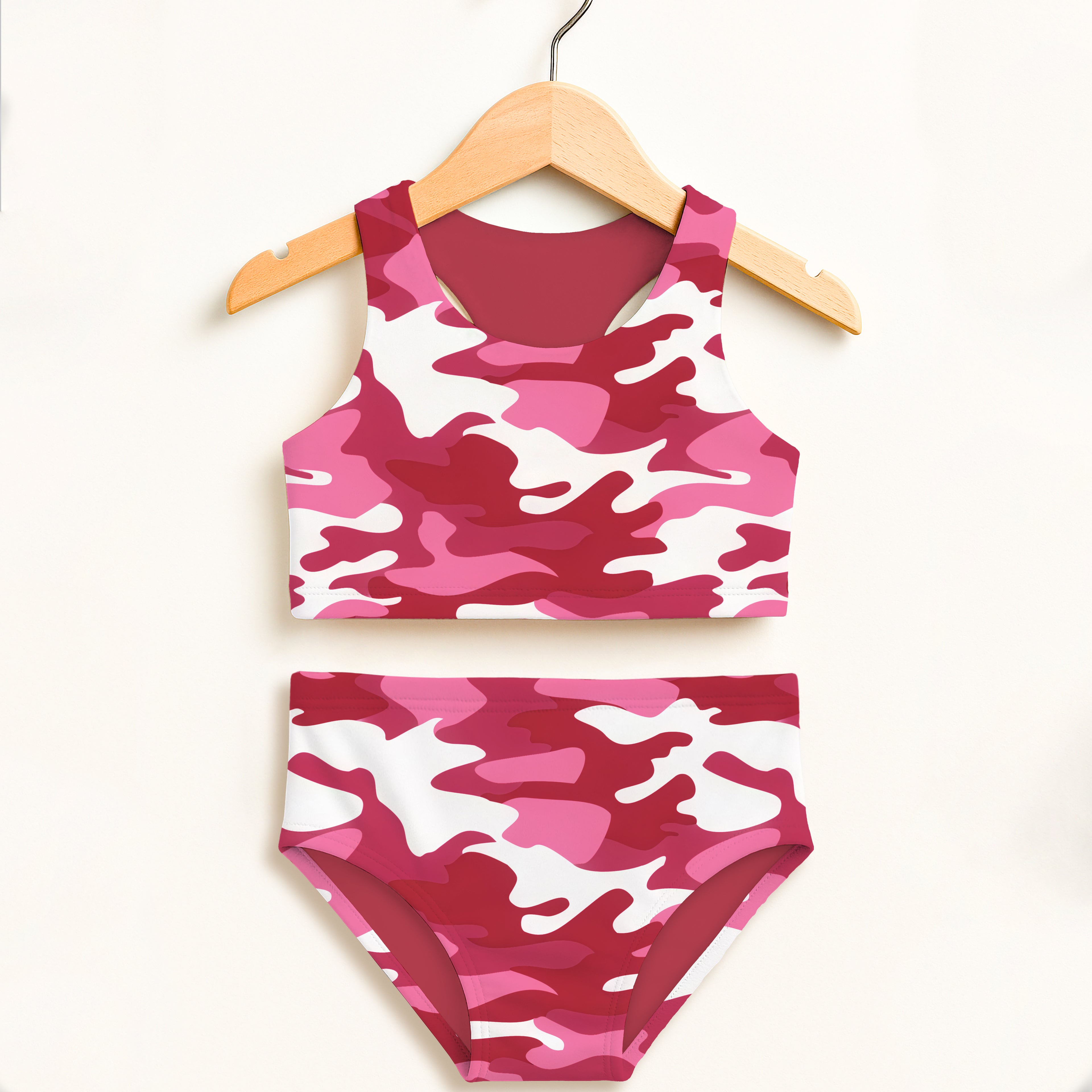 Girls bright pink and white camouflage two piece swimsuit hanging on wooden hanger with upf 50+ high waisted comfort