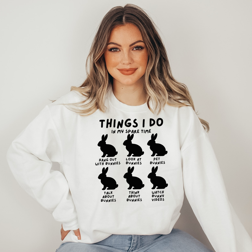 Woman wearing a white sweatshirt with black text and rabbit illustrations on a plain background