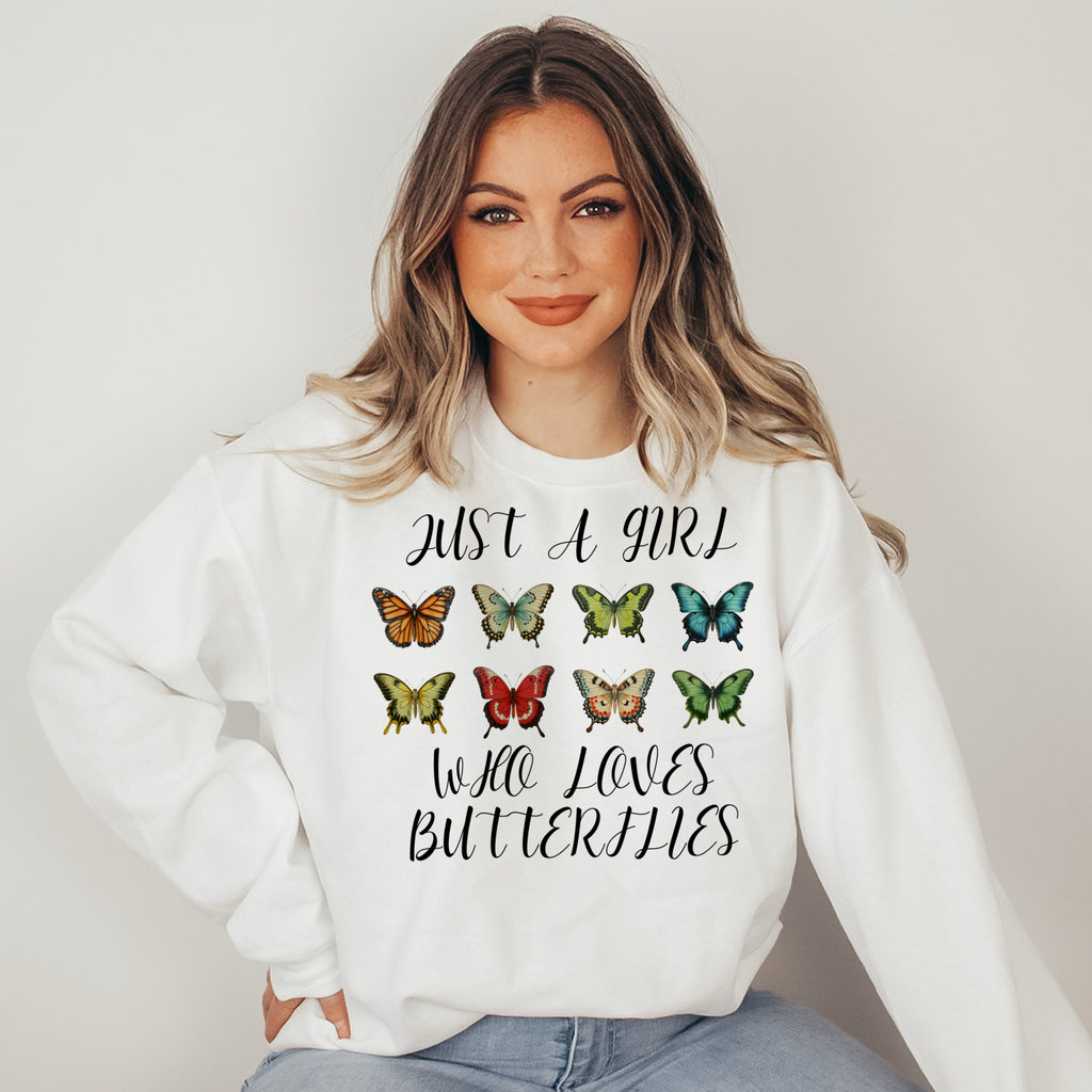Woman wearing a white sweatshirt with butterfly design and text on a plain background
