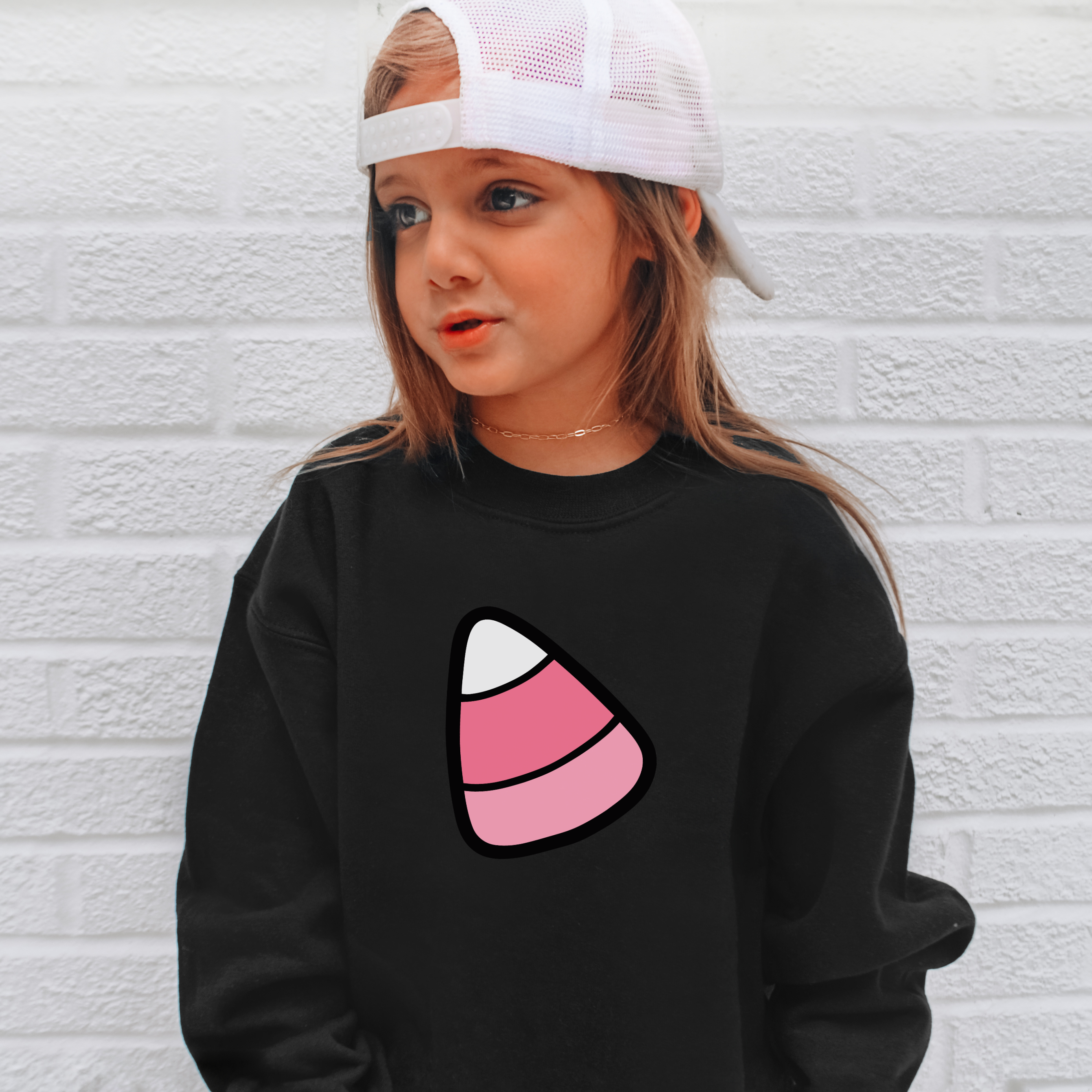 Black cotton kids sweatshirt with a pink white and black striped cartoon candy corn graphic for Halloween