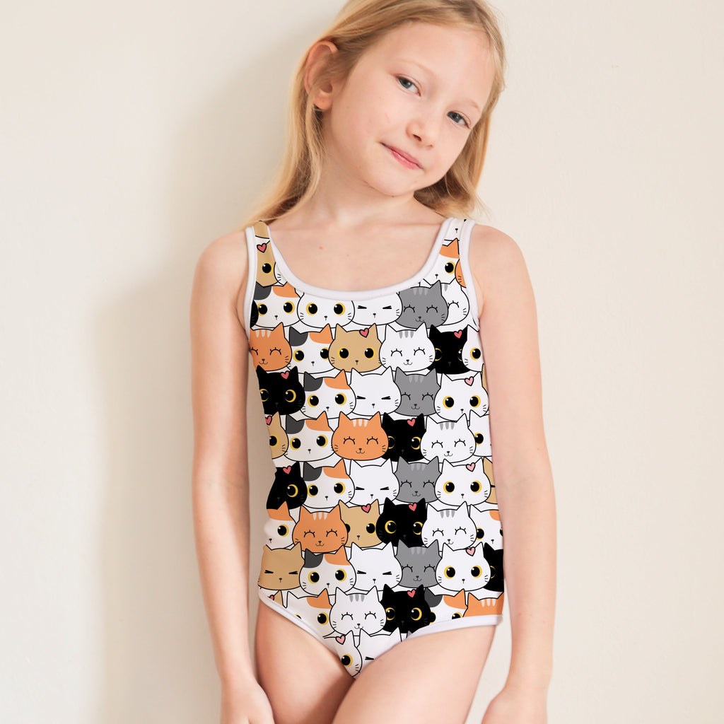 Young girl wearing a swimsuit with cat pattern on a plain background