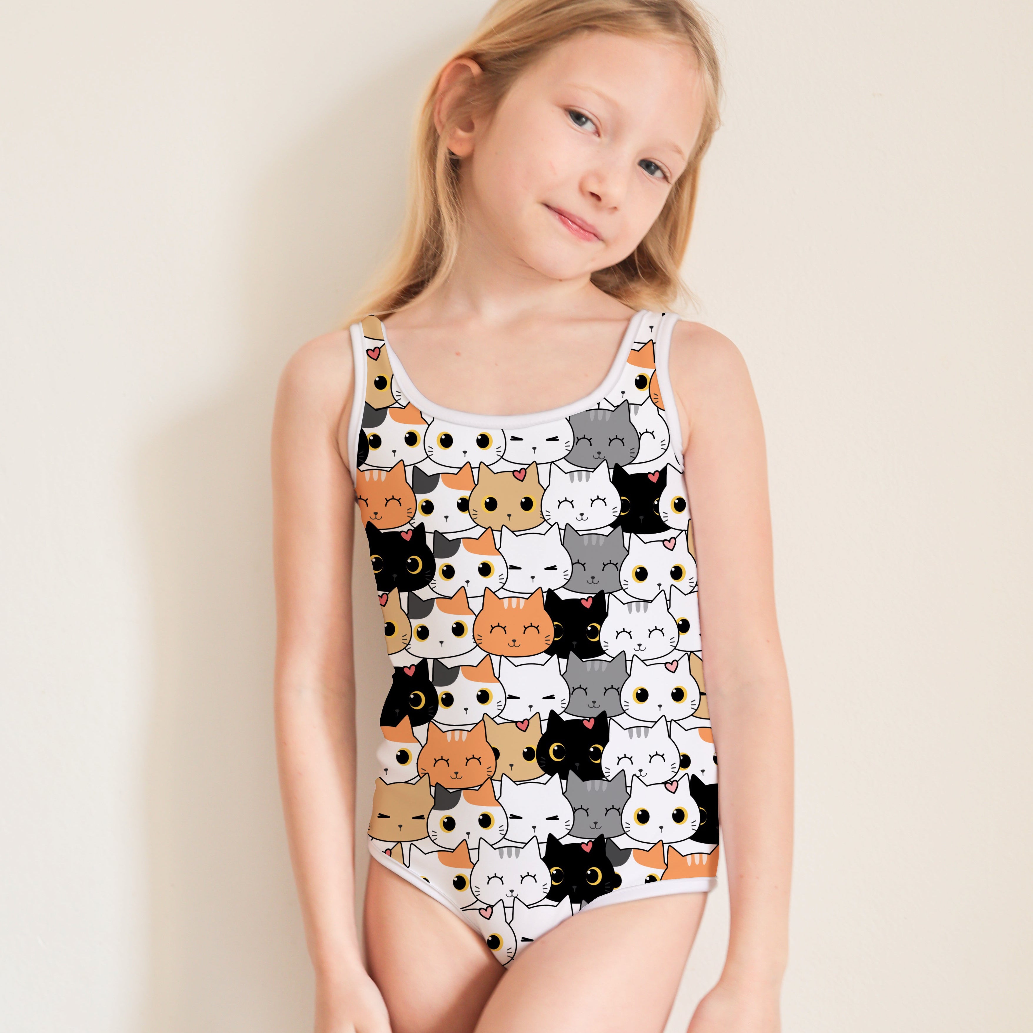 Young girl wearing a swimsuit with cat pattern on a plain background
