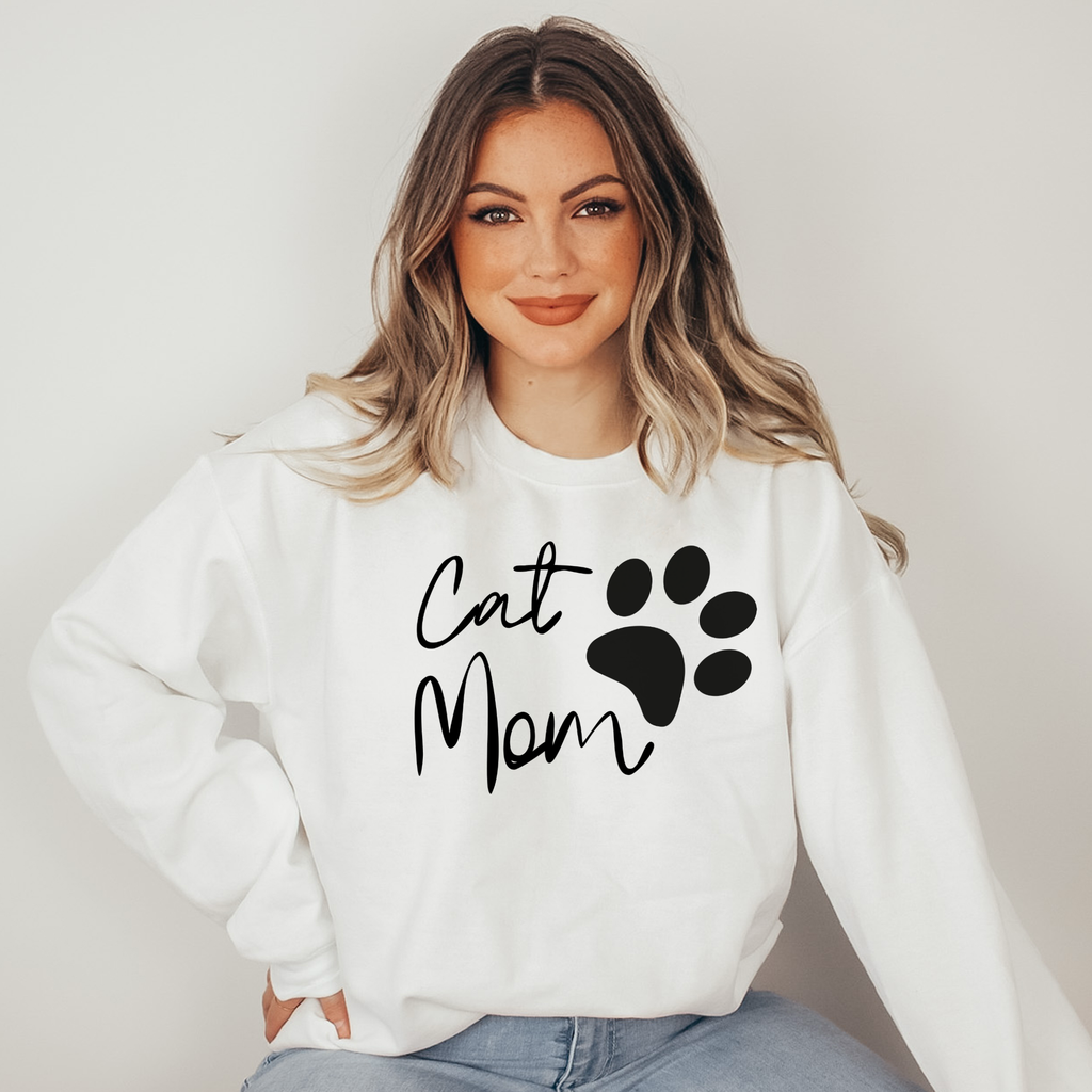 Woman wearing a white sweatshirt with 'Cat Mom' and a paw print design.