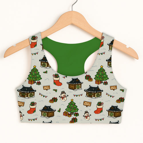 A festive gray girls Christmas village sports bra with green interior featuring snowmen and Korean-style houses pattern