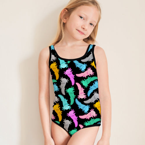 Young girl wearing a colorful axolotl patterned leotard against a plain background