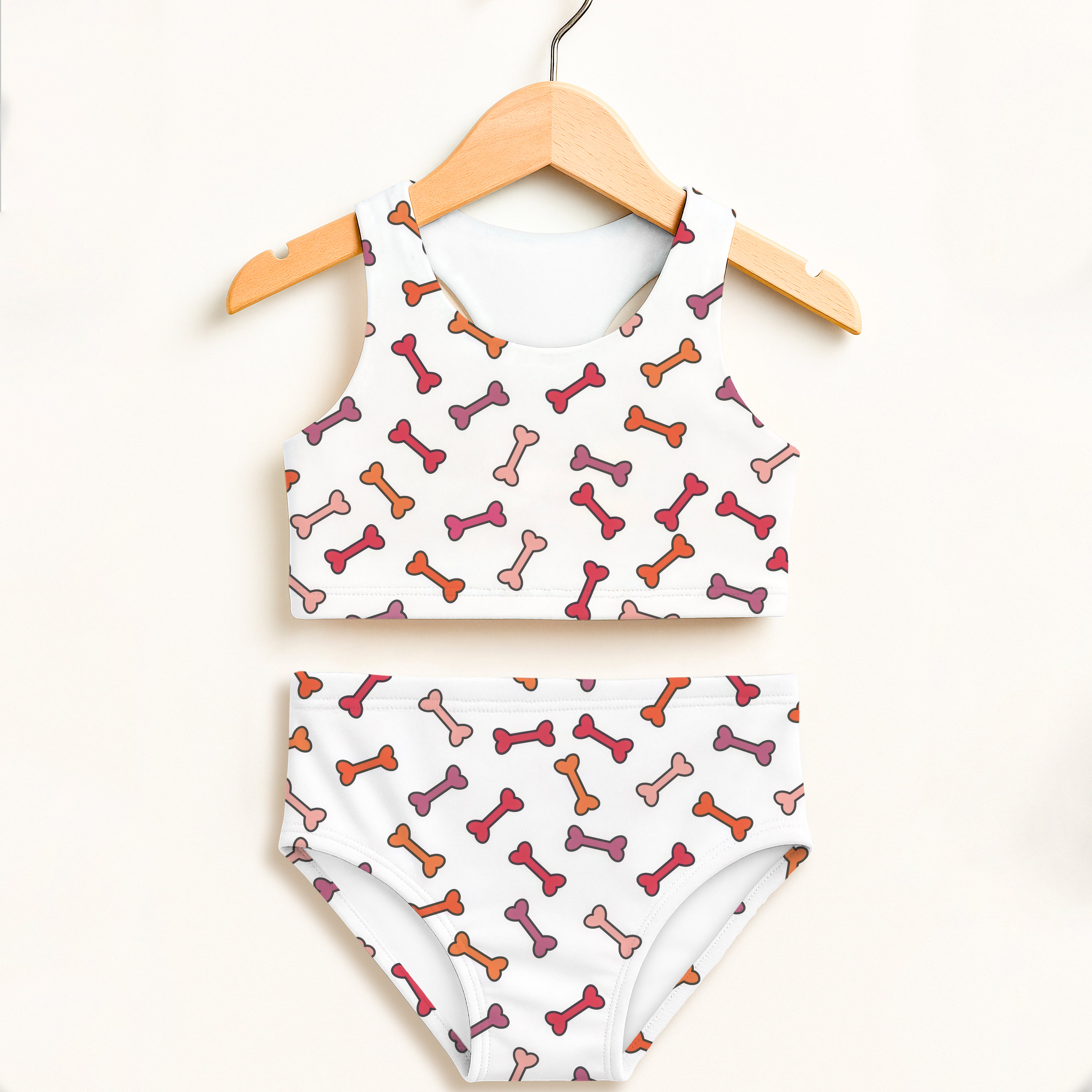 White girls dog bone two piece swimsuit with playful pink orange mauve bones and double layered upf 50+ high waisted design