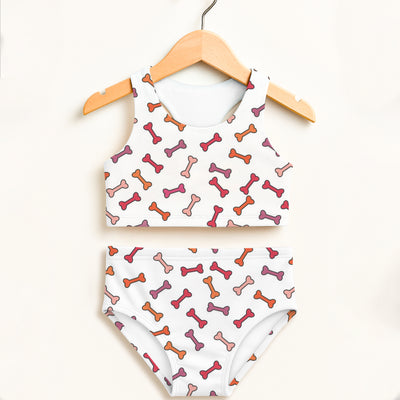 White girls dog bone two piece swimsuit with playful pink orange mauve bones and double layered upf 50+ high waisted design