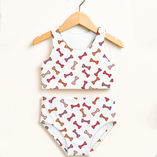 White girls dog bone two piece swimsuit with playful pink orange mauve bones and double layered upf 50+ high waisted design